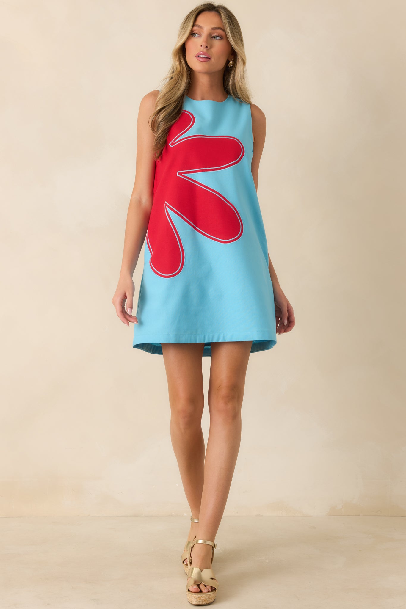 Sleeveless mini shift dress showcasing bold red floral-inspired appliqué, a comfortable lined construction, and an effortless relaxed fit.