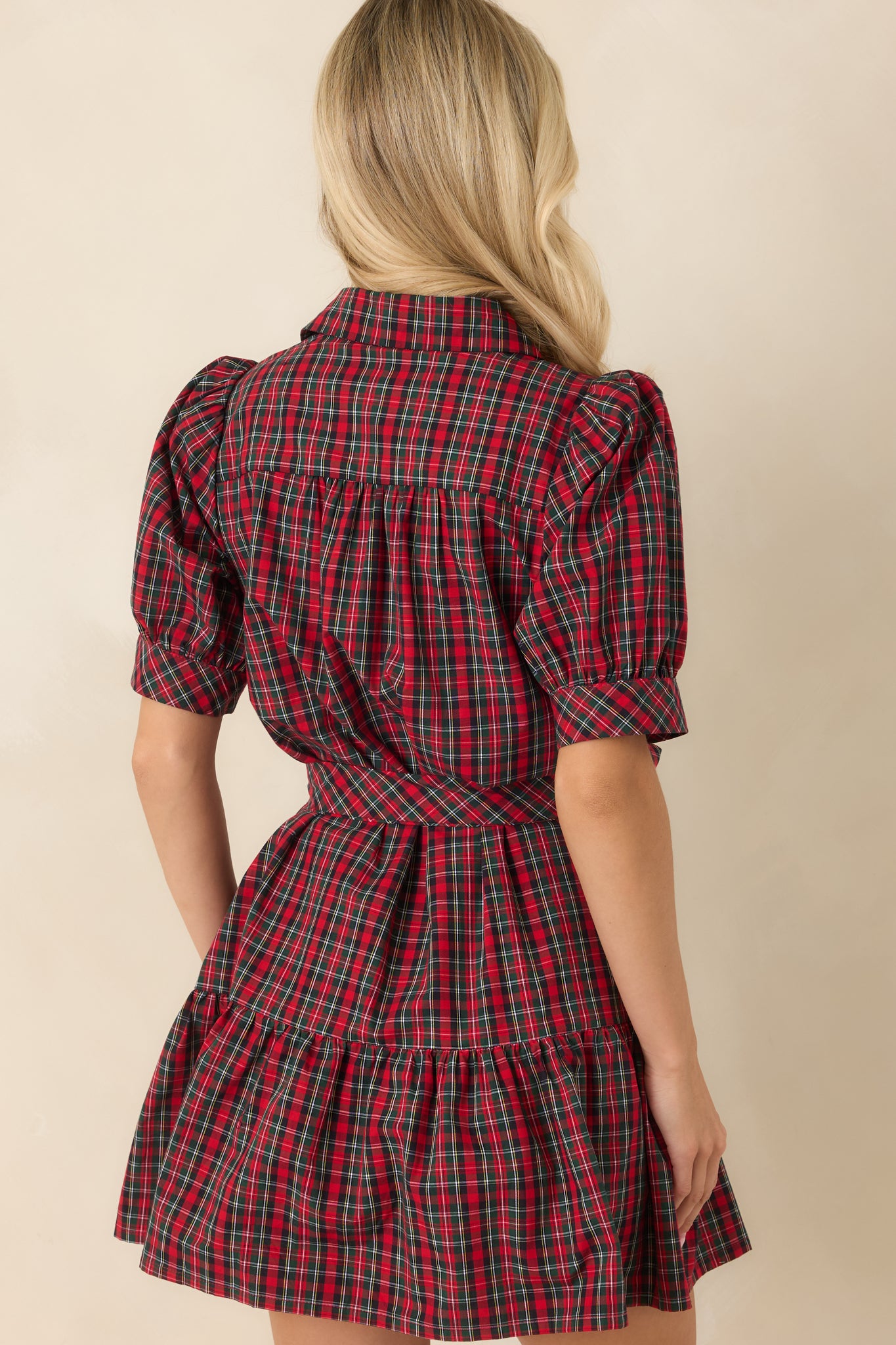 Rear view of the red and green plaid mini dress featuring puff sleeves, removable tie belt, tiered skirt, and flowing silhouette.