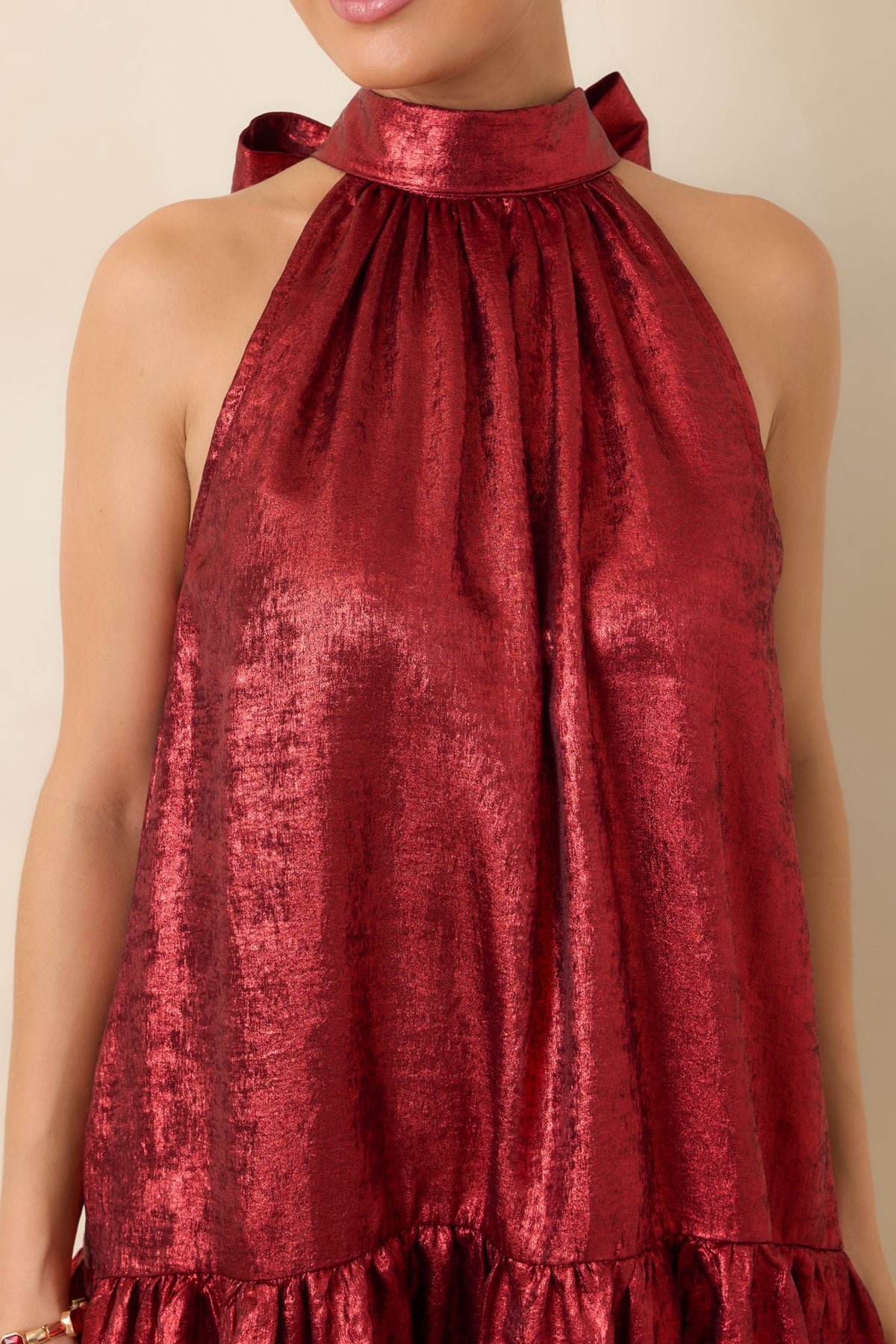 Close-up of the red mini dress showing the gathered halter neckline and lustrous fabric texture.