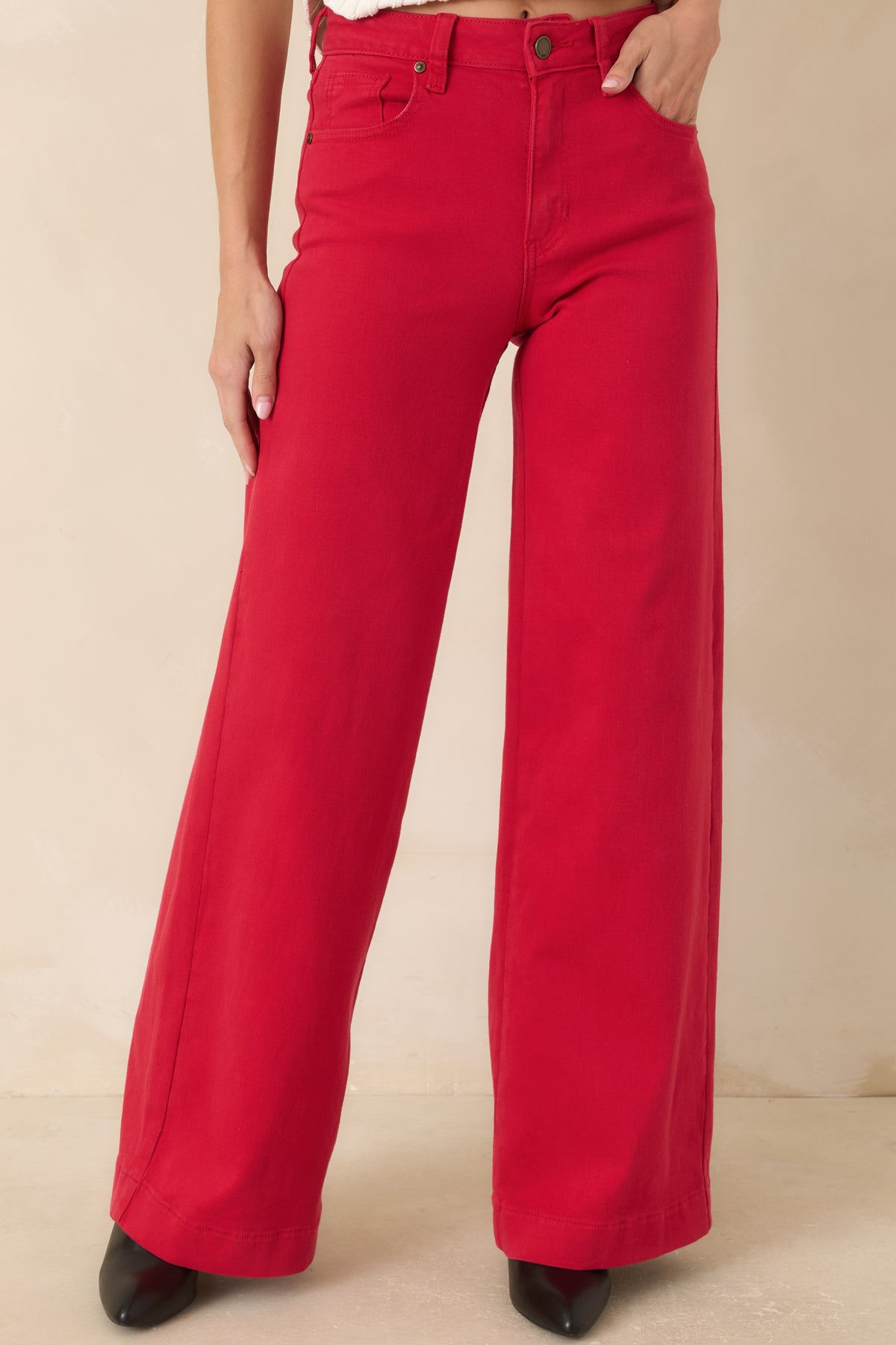 Detailed view of the vibrant red jeans featuring classic five-pocket styling, button-and-zip closure, and structured waistband.