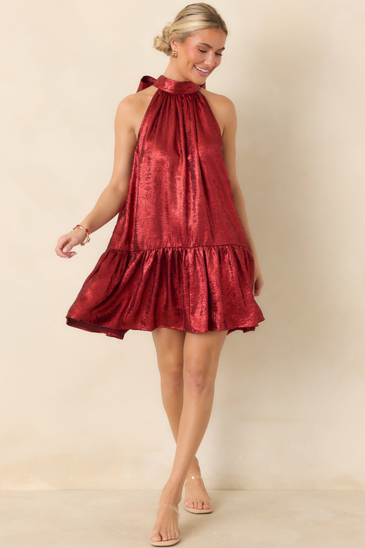 Red satin-look mini dress featuring a gathered halter neckline, flowing swing silhouette, and wide ruffle hem.