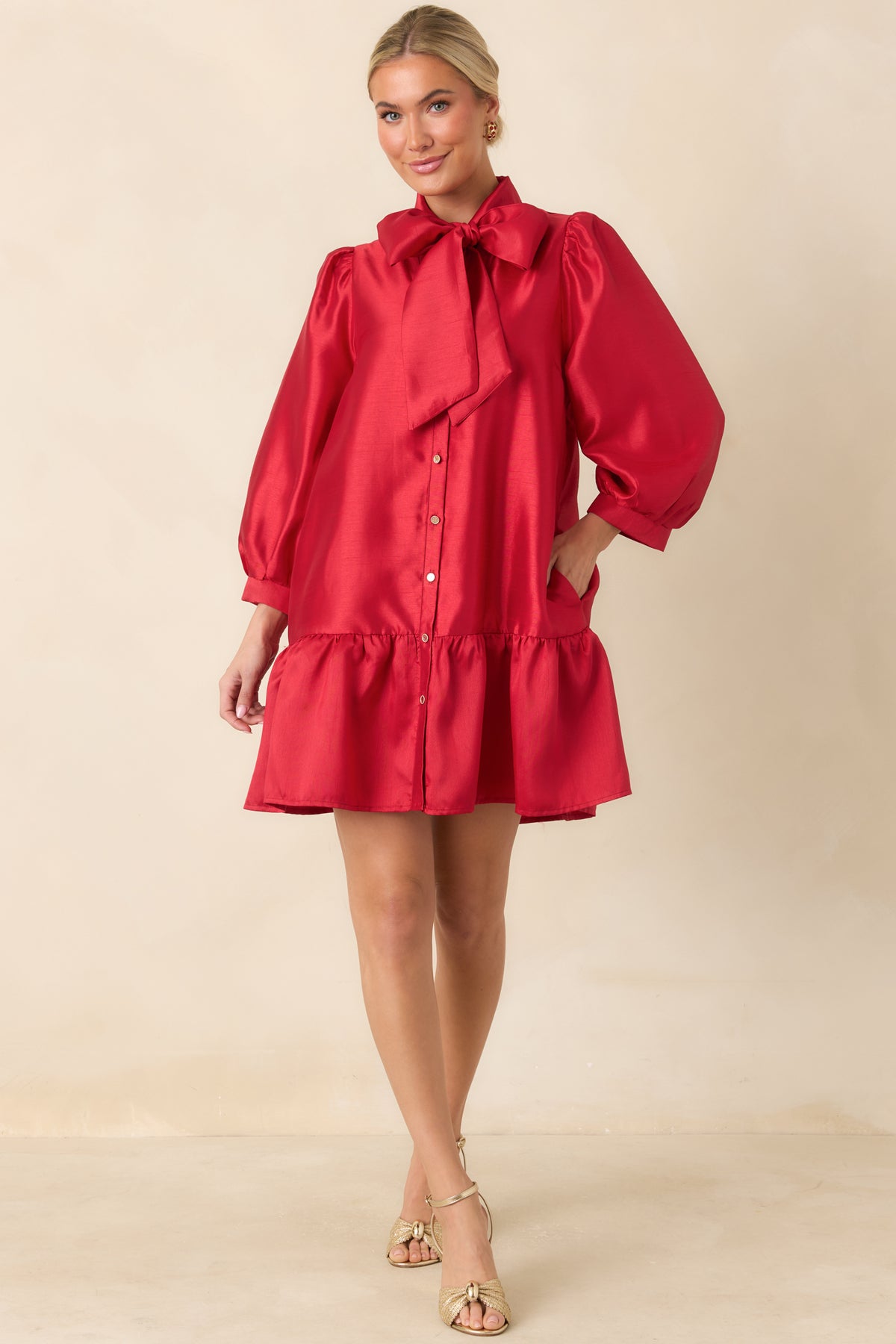 Lustrous red dress with a relaxed silhouette, banded puff sleeve cuffs, and a gathered ruffle hem.