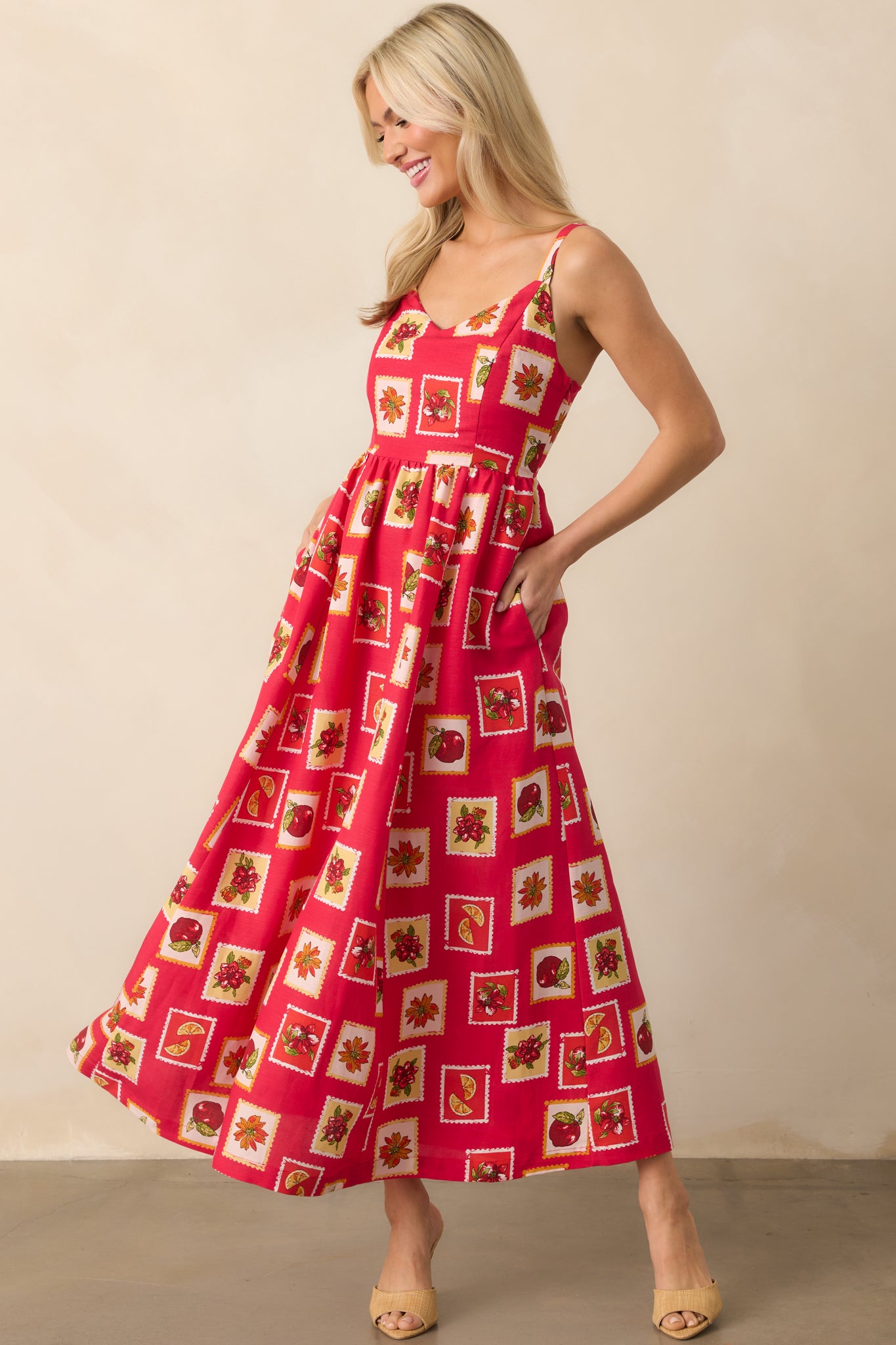 Red maxi dress featuring stamp-inspired patchwork with floral and fruit motifs, sweetheart neckline, and adjustable straps shown front-facing.