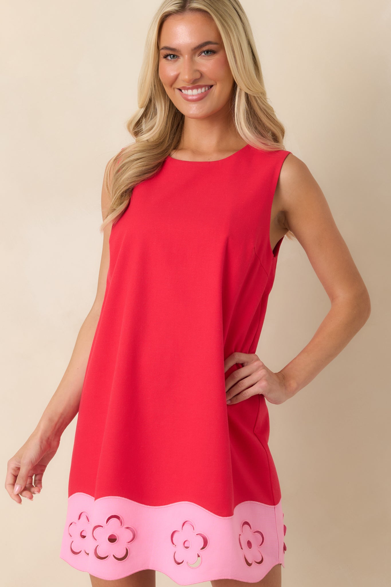 Red mini dress highlighting the contrasting pink hem with intricate floral cutout accents.