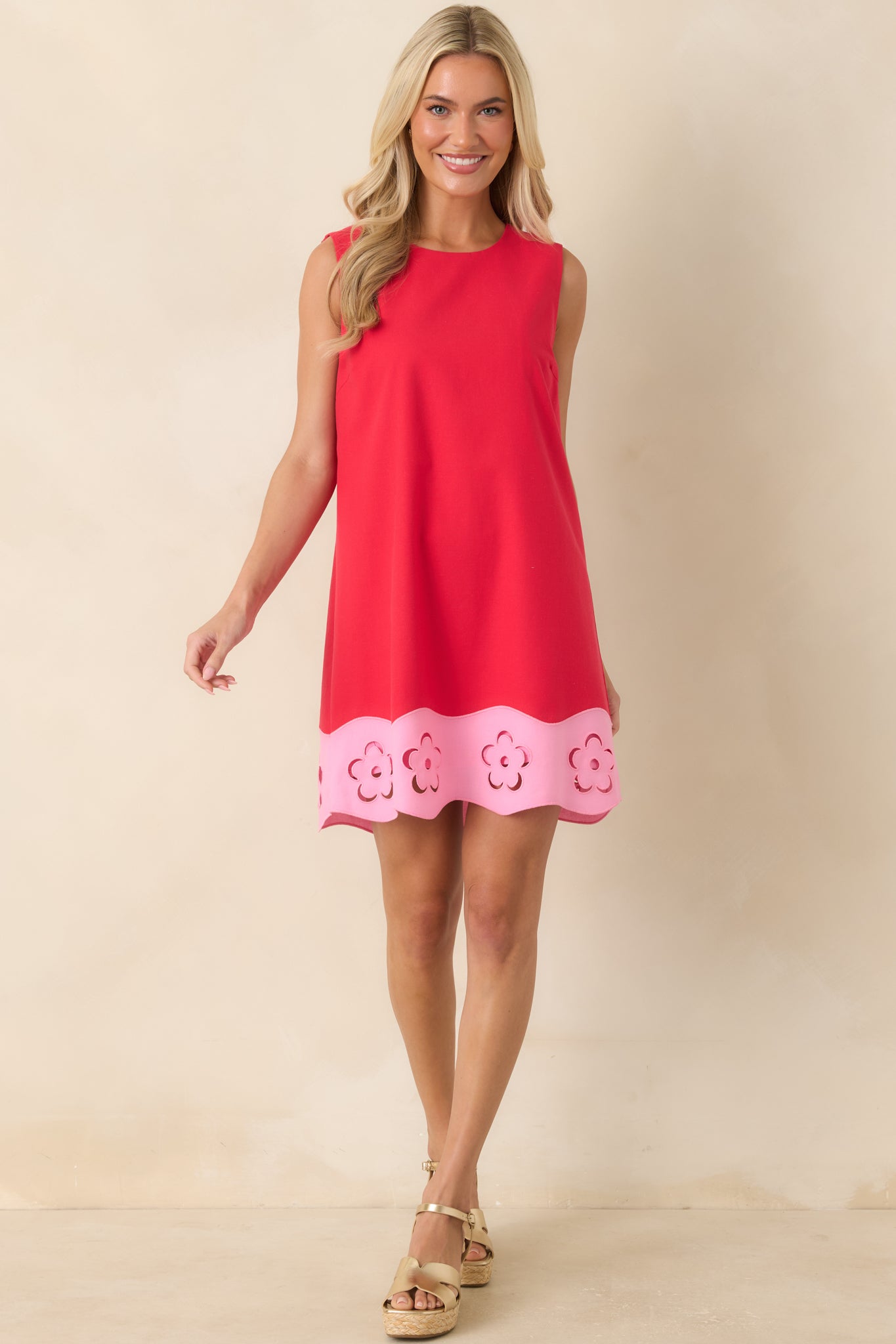 Red mini dress featuring a round neckline, sleeveless silhouette, and pink floral cutout hem detailing.