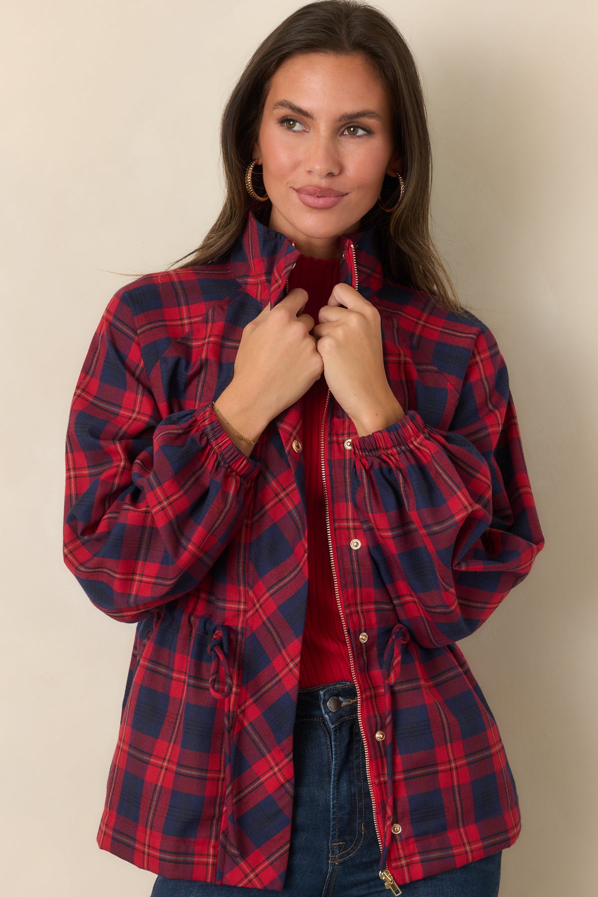 Red and navy plaid jacket with a defined waist created by its adjustable drawstring.