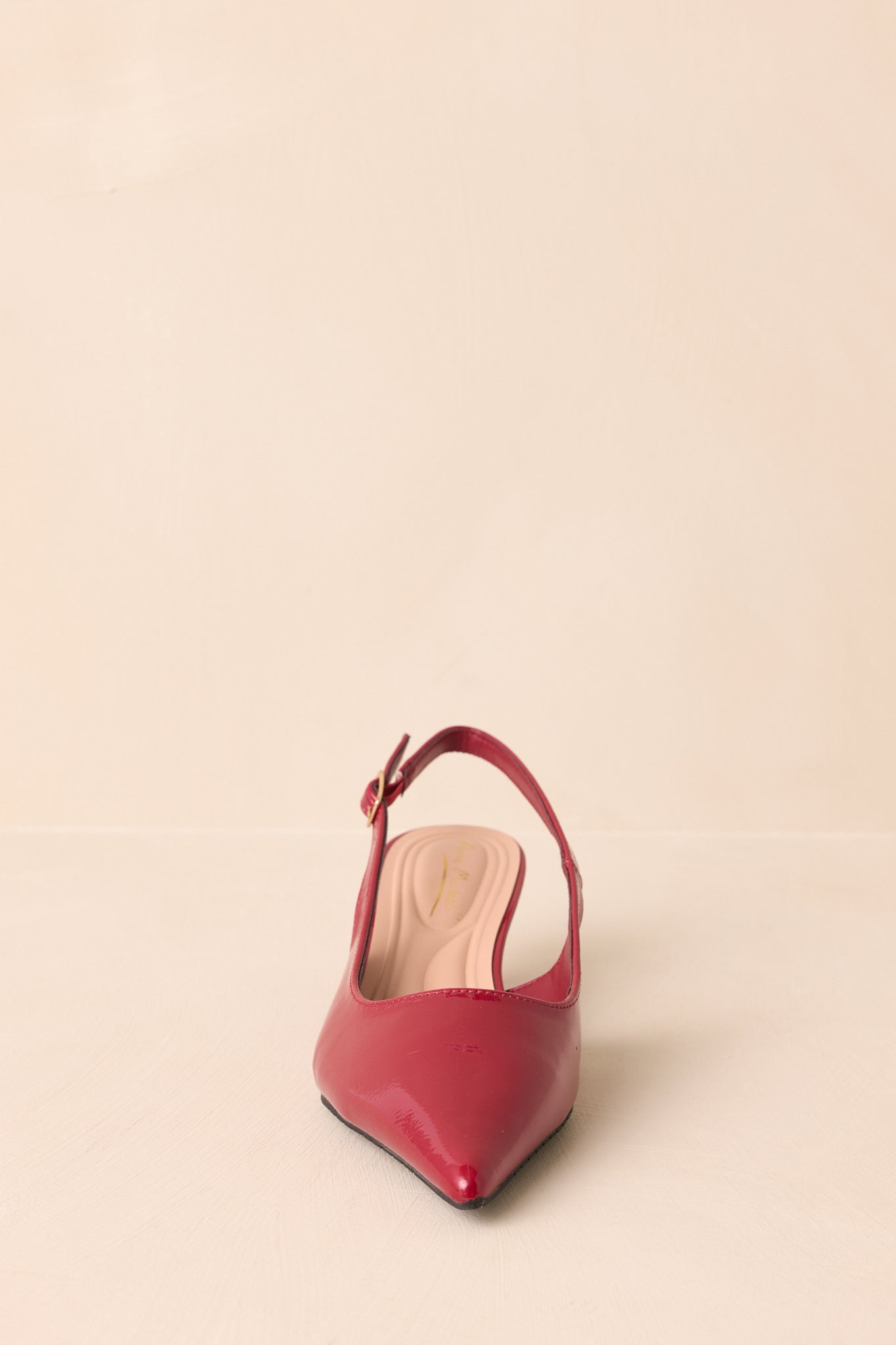 Red patent slingback heels displayed at a front angle with pointed toe in view.