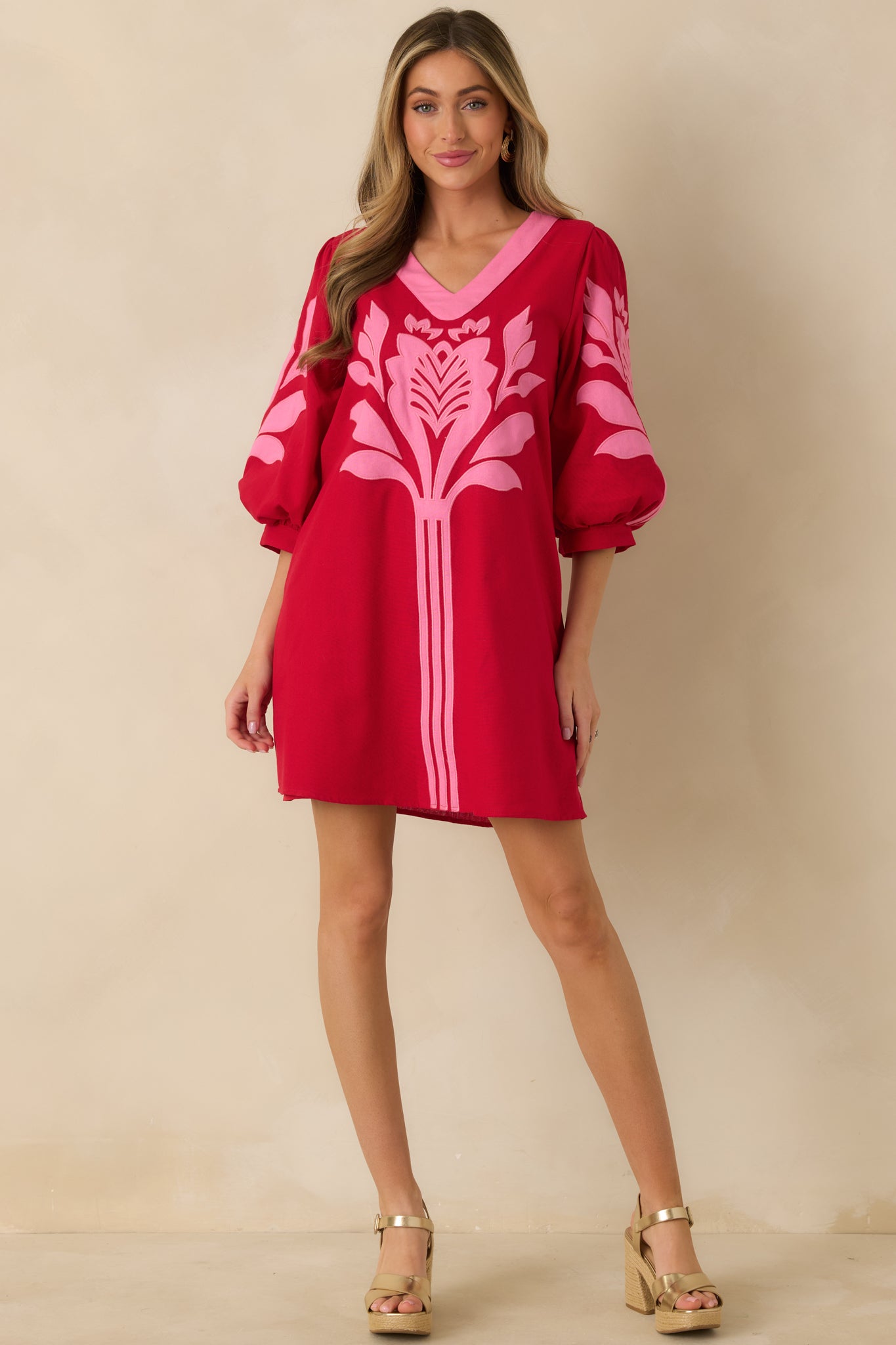 Mini dress in red and pink featuring a V-neckline with contrast trim, short puff sleeves, gathered cuffs, and a loose, easy silhouette.