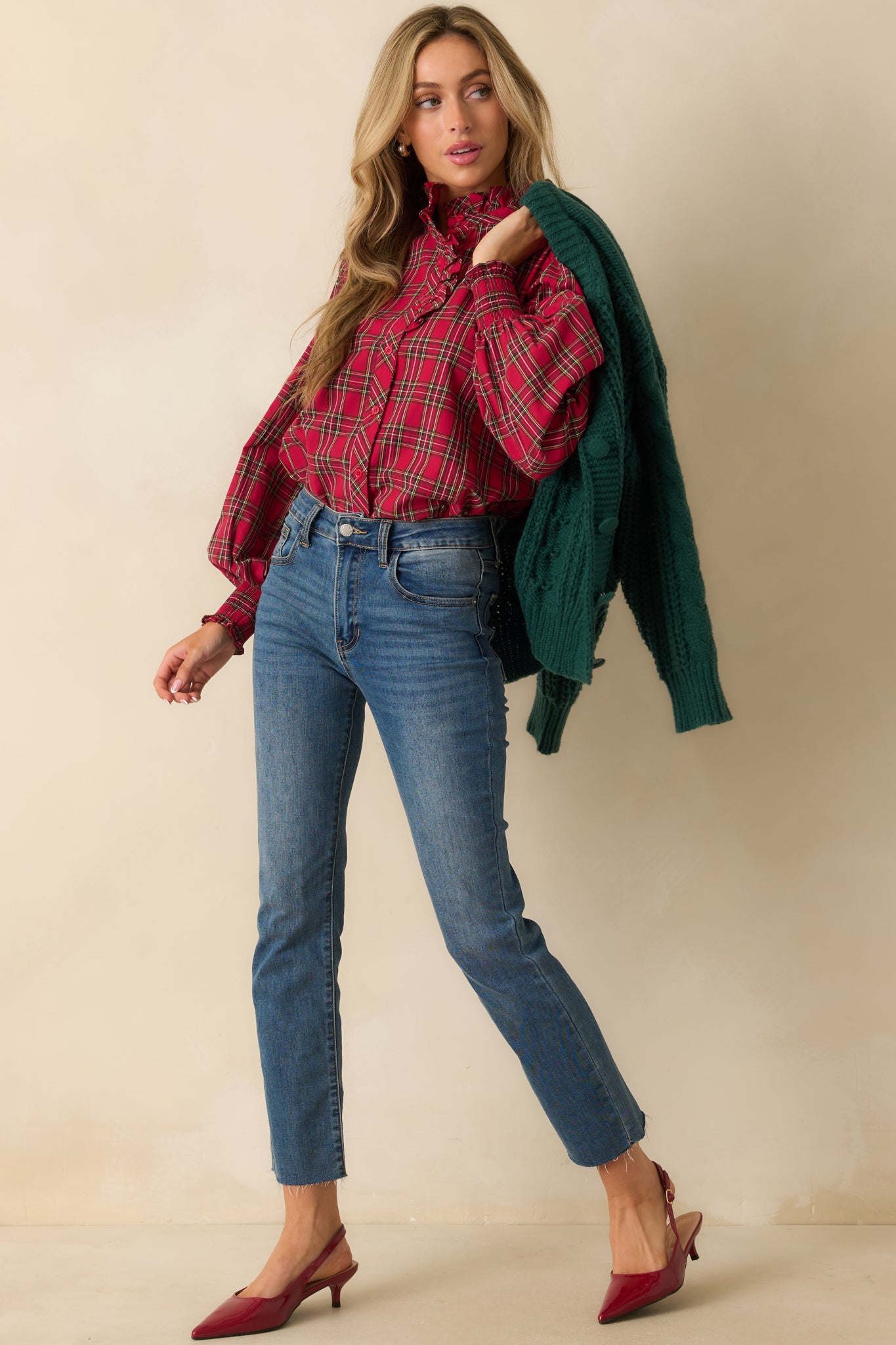 Red plaid blouse with long puff sleeves, smocked cuffs, and delicate ruffle detail framing the neck.
