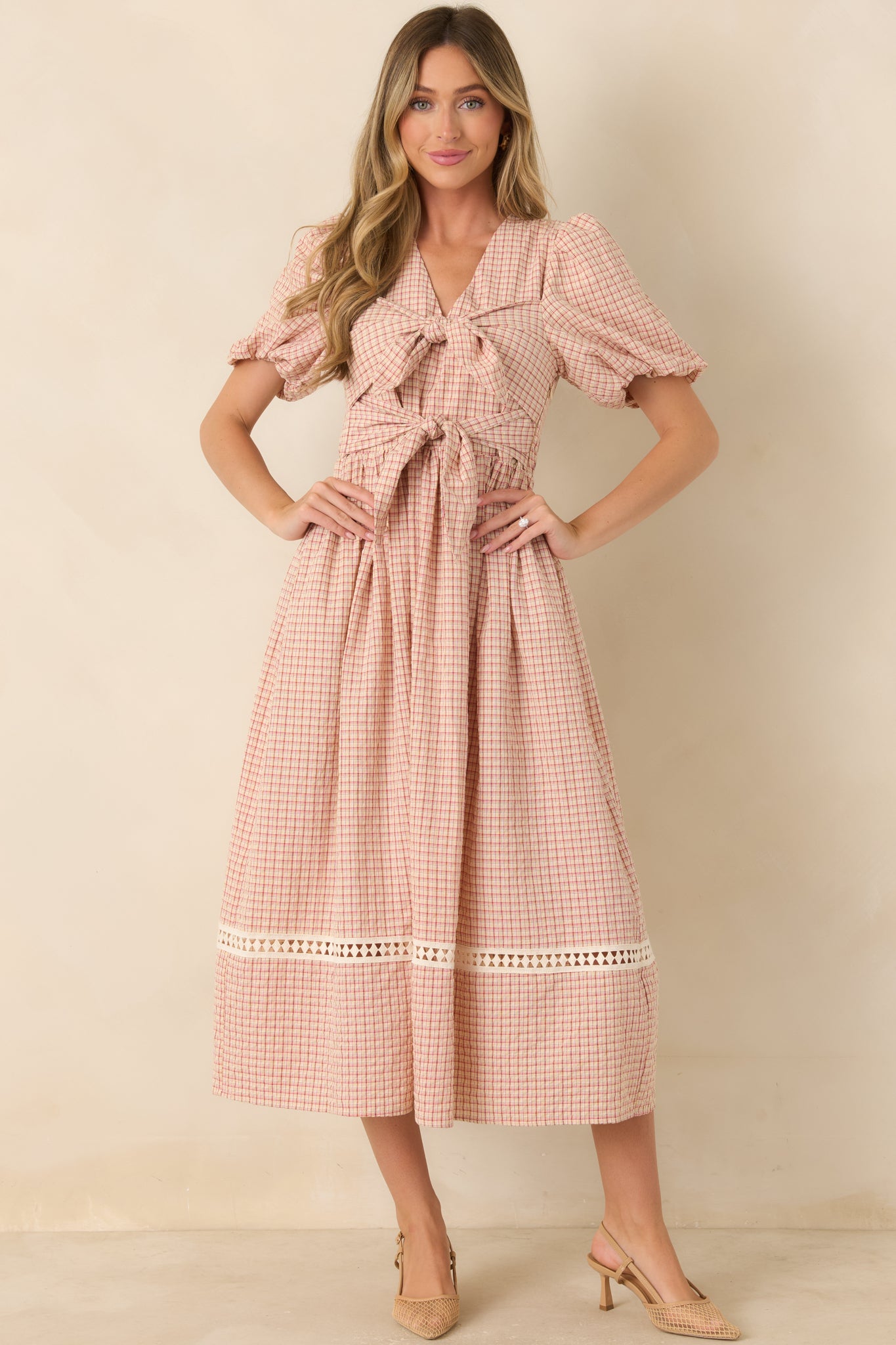 Red and beige checked midi dress with playful oversized front ties, puff sleeves, a defined elastic waist, and a full skirt finished with crochet detailing.