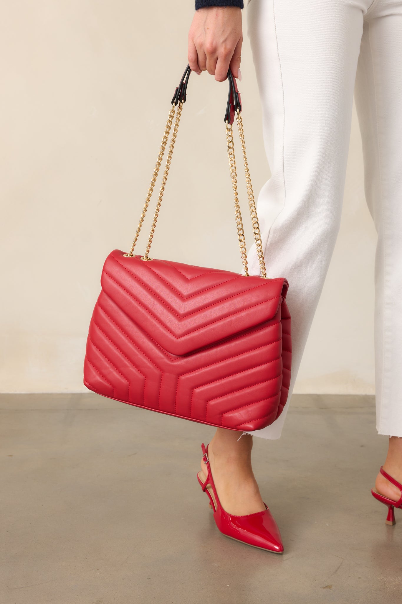 Another angle of the red quilted handbag, showcasing the quilted design, gold chain handles, and the matching red wallet placed inside the bag, with the snap flap and zipper closure visible.