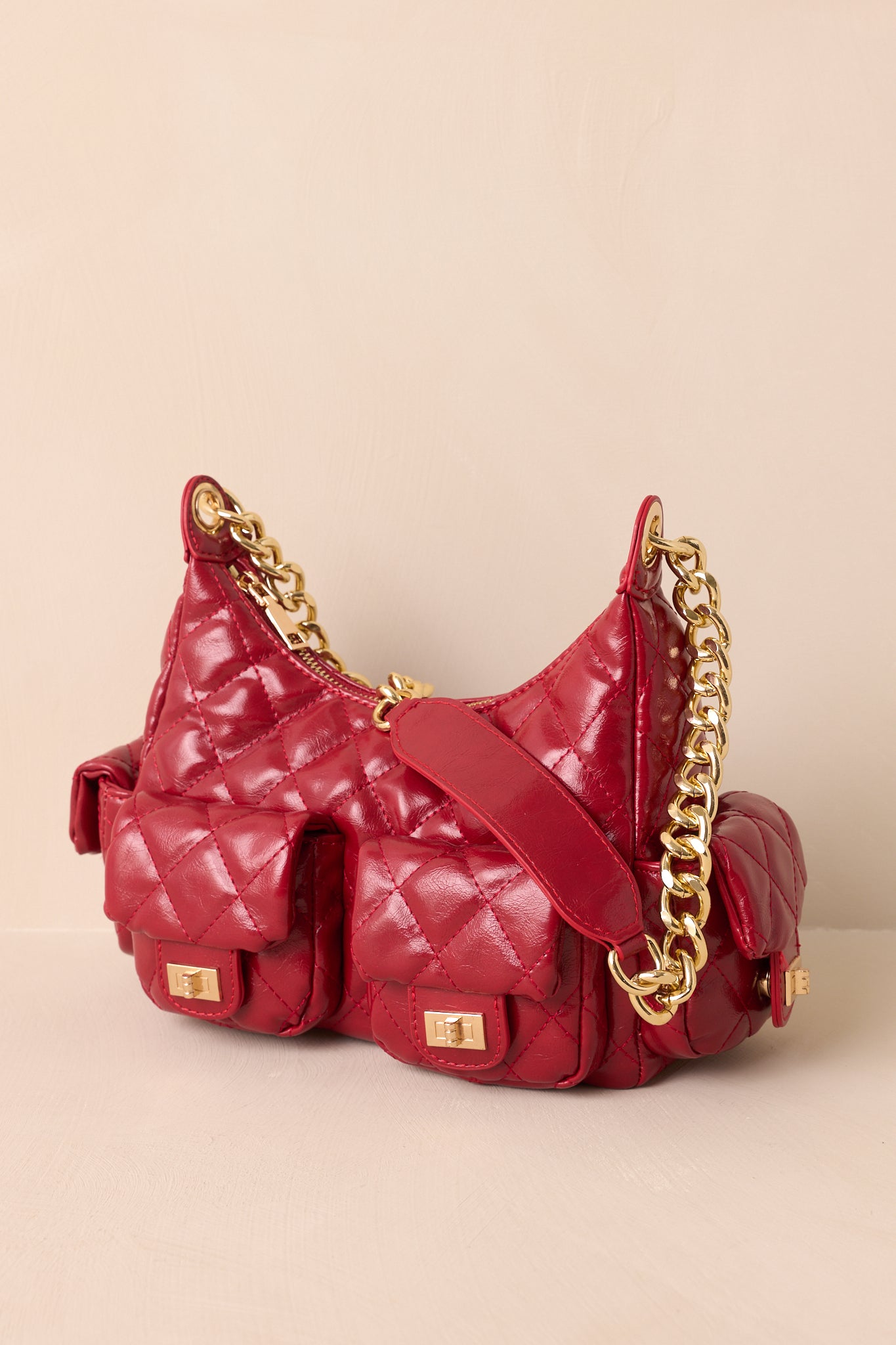 A full view of the red quilted handbag showing the structured silhouette and gold chain shoulder strap.