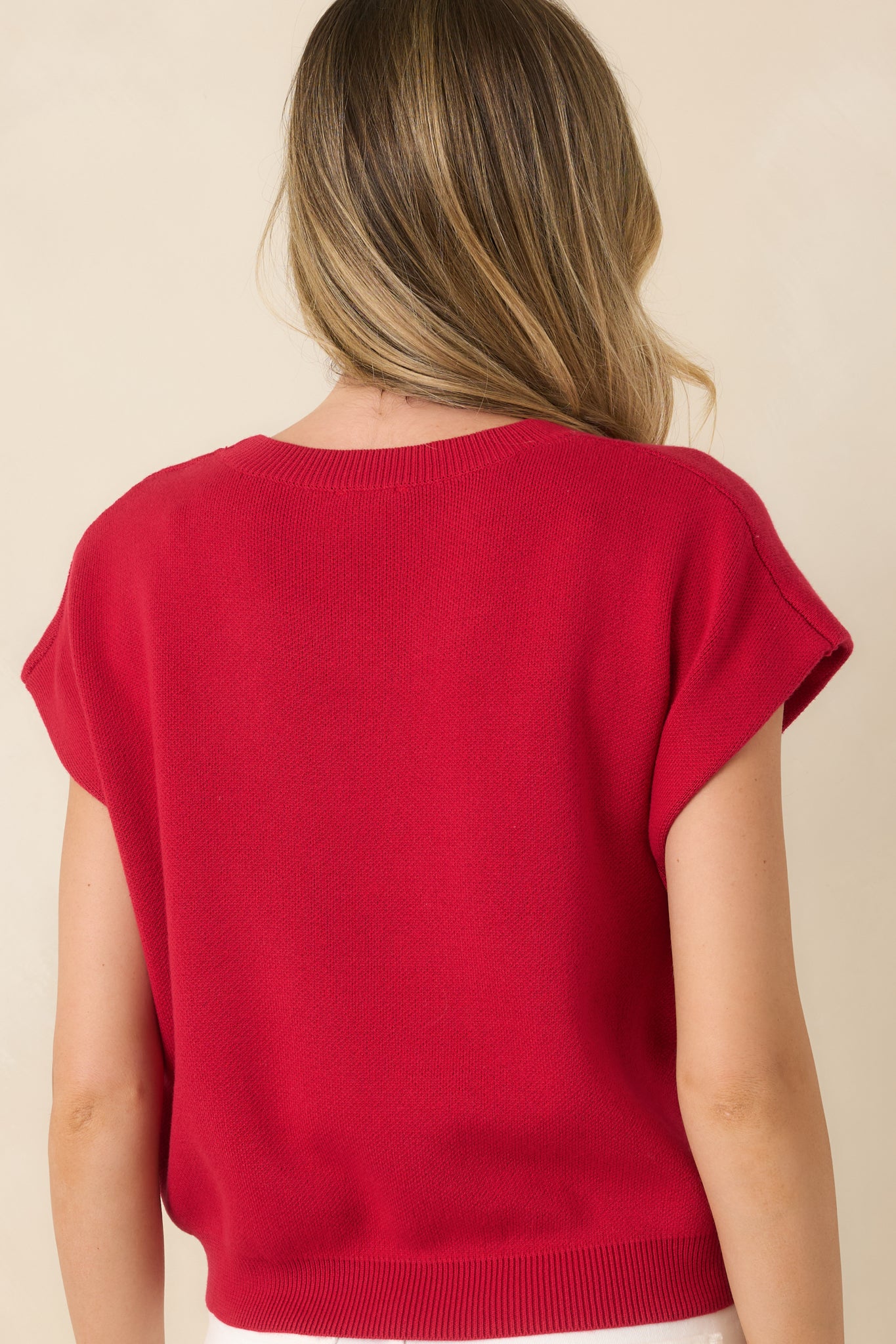 Rear view of the red knit sweater featuring a relaxed fit and clean cap sleeve silhouette.