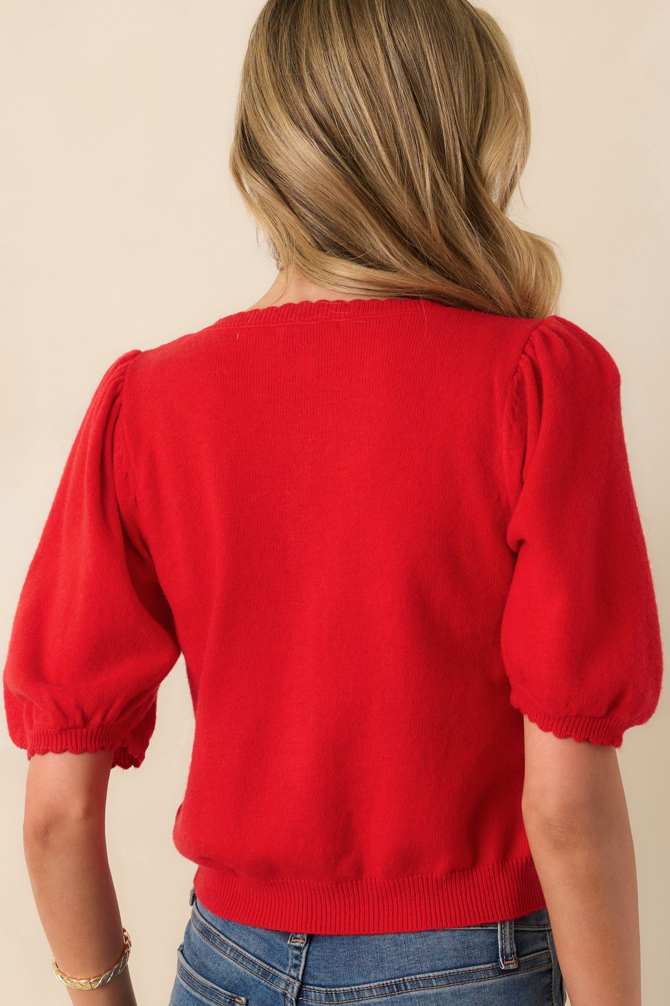 A view from behind showing the smooth knit construction, short sleeves, and simple silhouette of the cardigan.