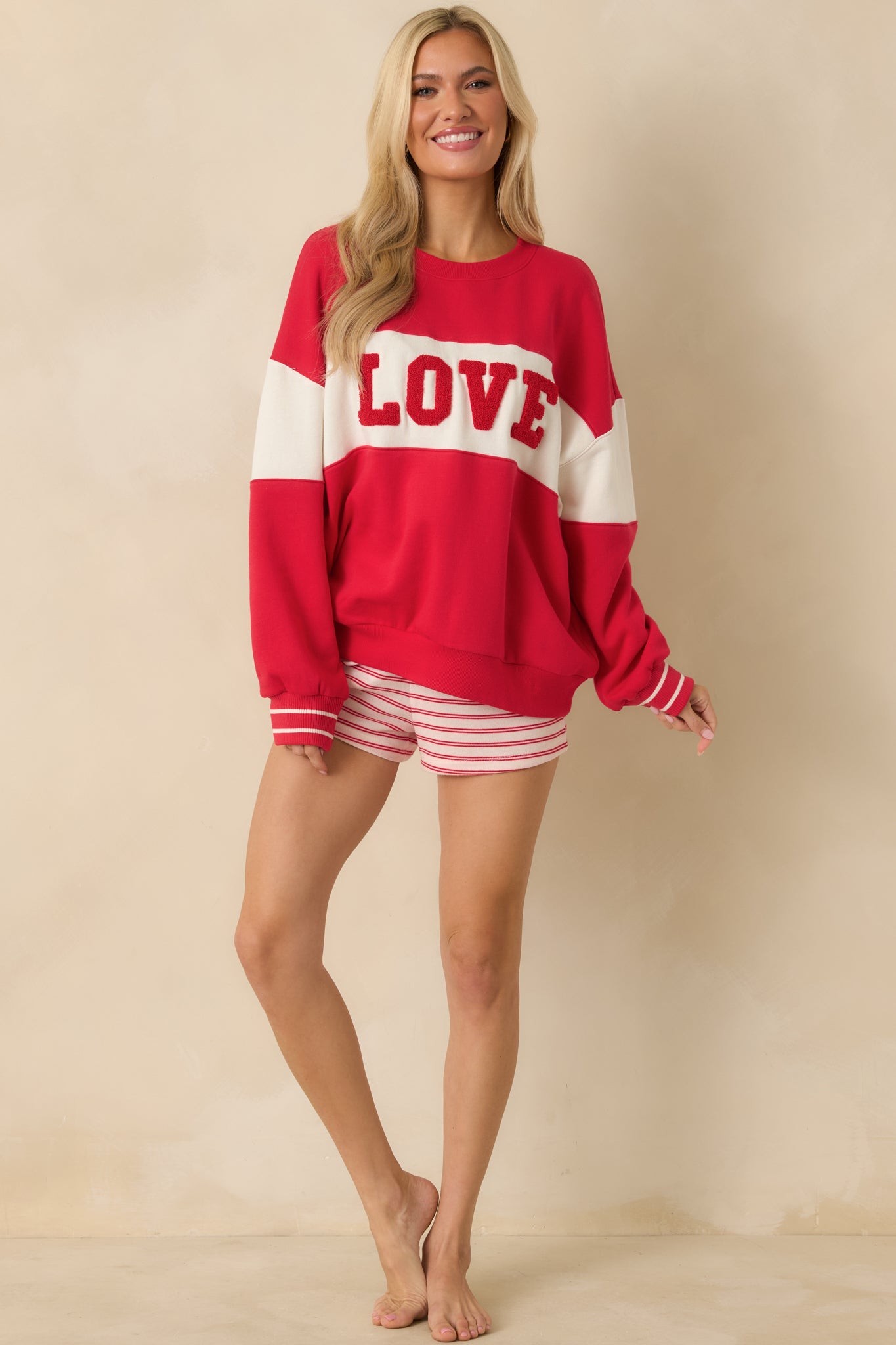 Red sweatshirt showcasing contrasting ivory panels and textured “LOVE” lettering on the front