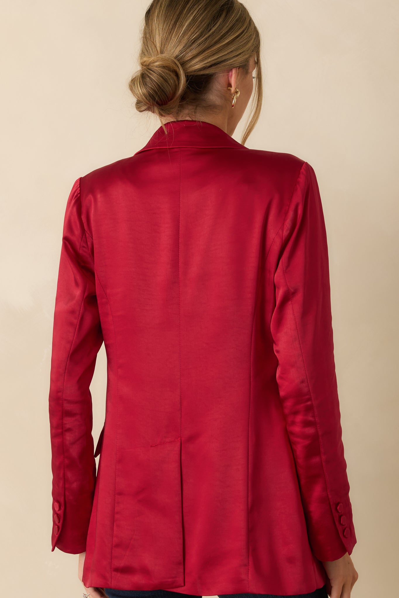 Rear view of the red tailored blazer highlighting the lightly structured fit and long sleeves.