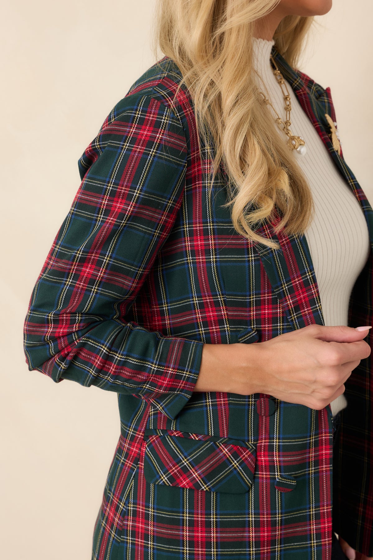 Close-up of the red tartan blazer showing its plaid fabric, notched lapels, and button-front detailing.