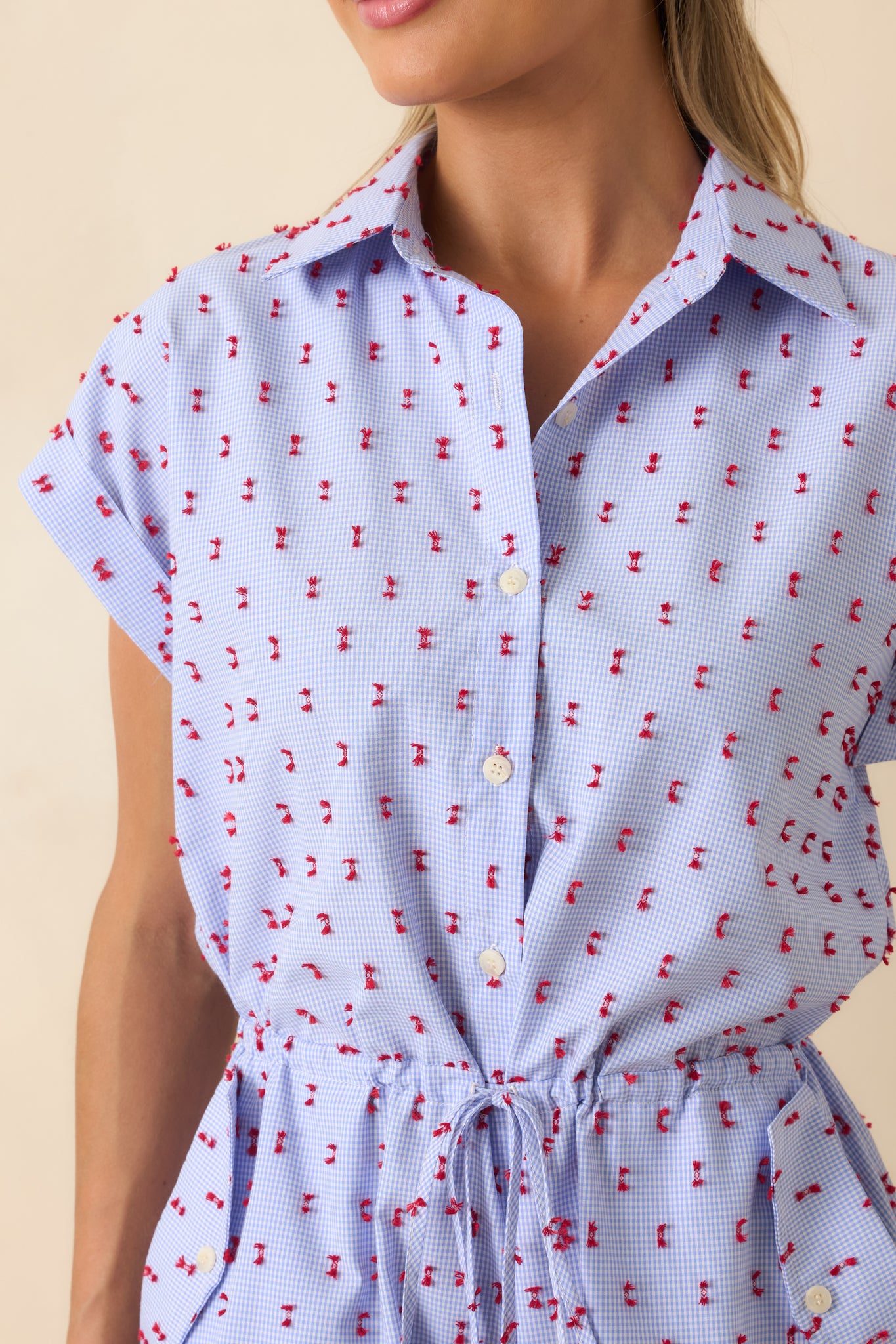 Close-up of the red tufted embroidery, gingham pattern, and button detailing across the romper.