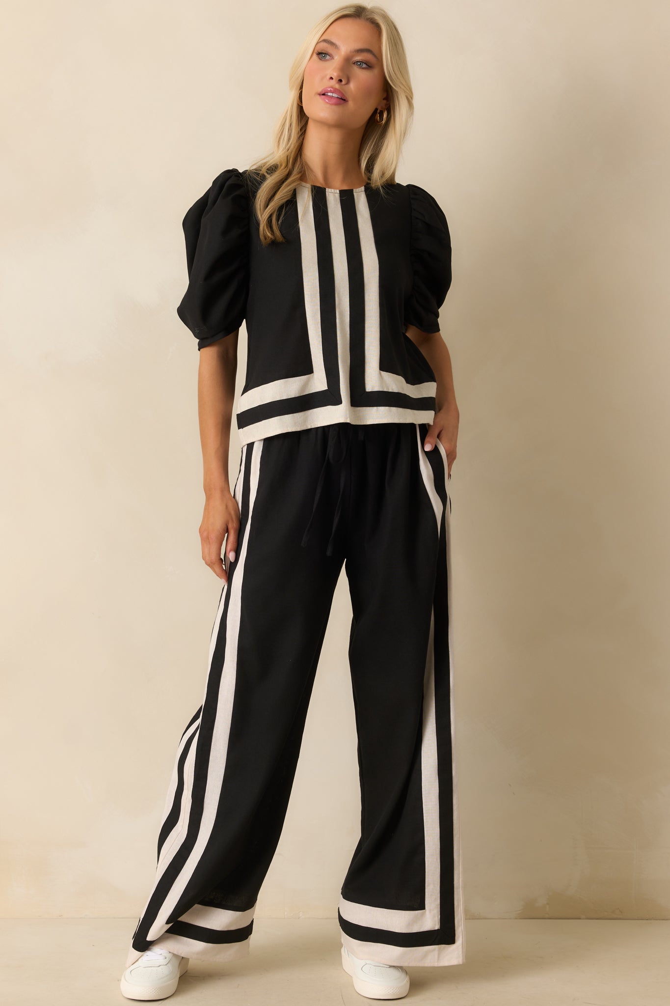 Relaxed-fit black blouse with contrast ivory edging along the neckline and sleeves for a polished finish