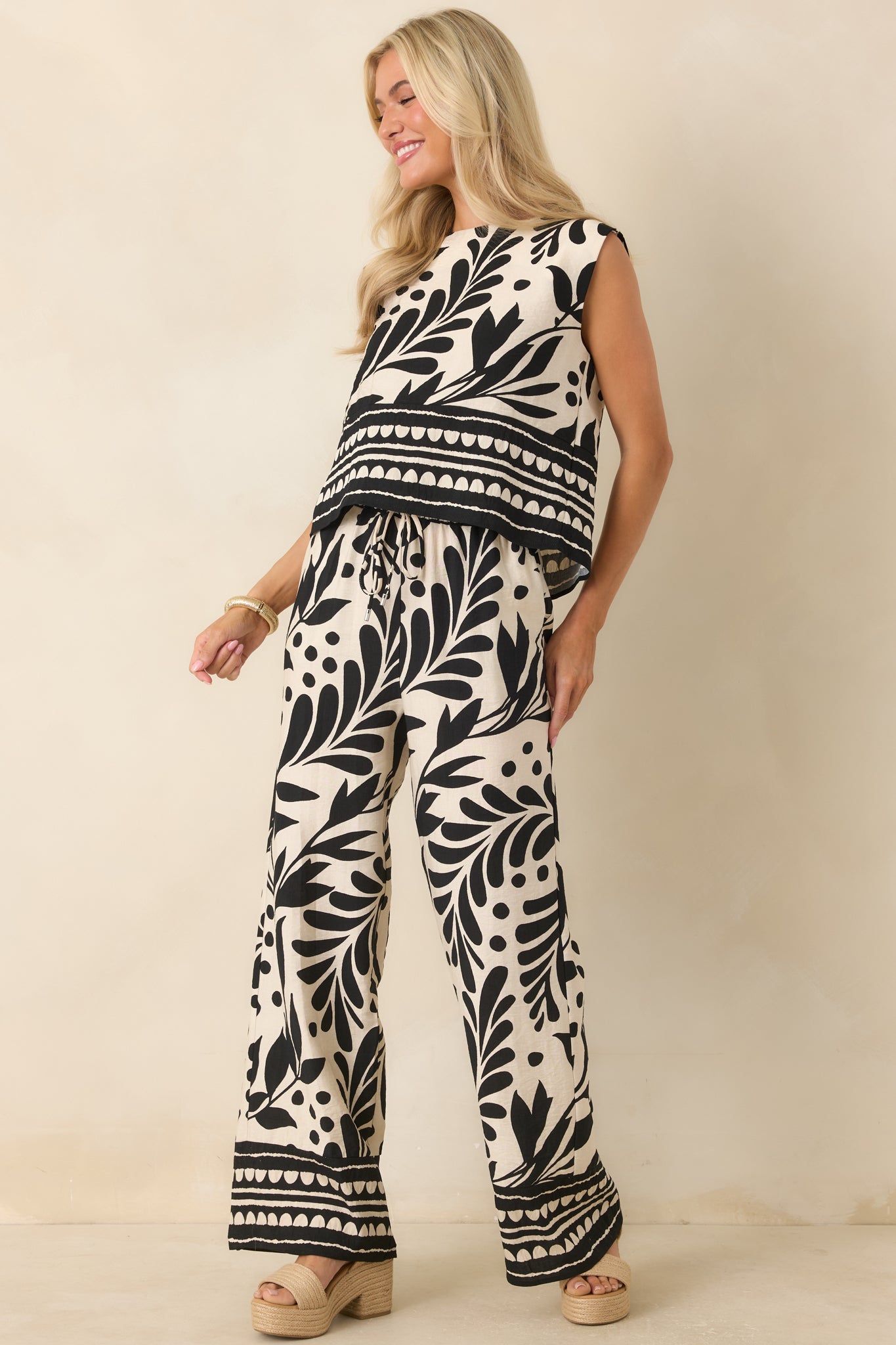 Relaxed-fit woven pants showcasing an elastic waistband with drawstring, side pockets, and bold botanical pattern throughout.