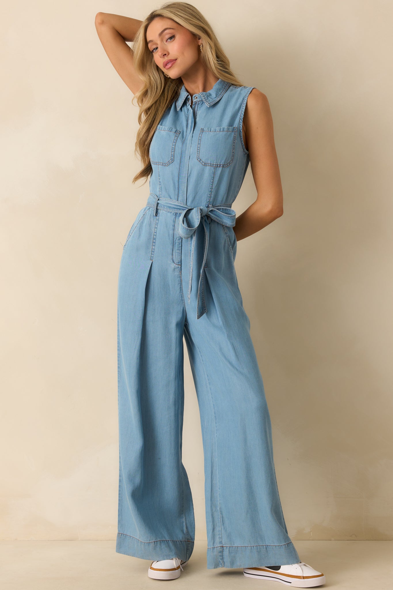 Relaxed-fit chambray jumpsuit with collared neckline, functional breast and hip pockets, and an adjustable self-tie belt.