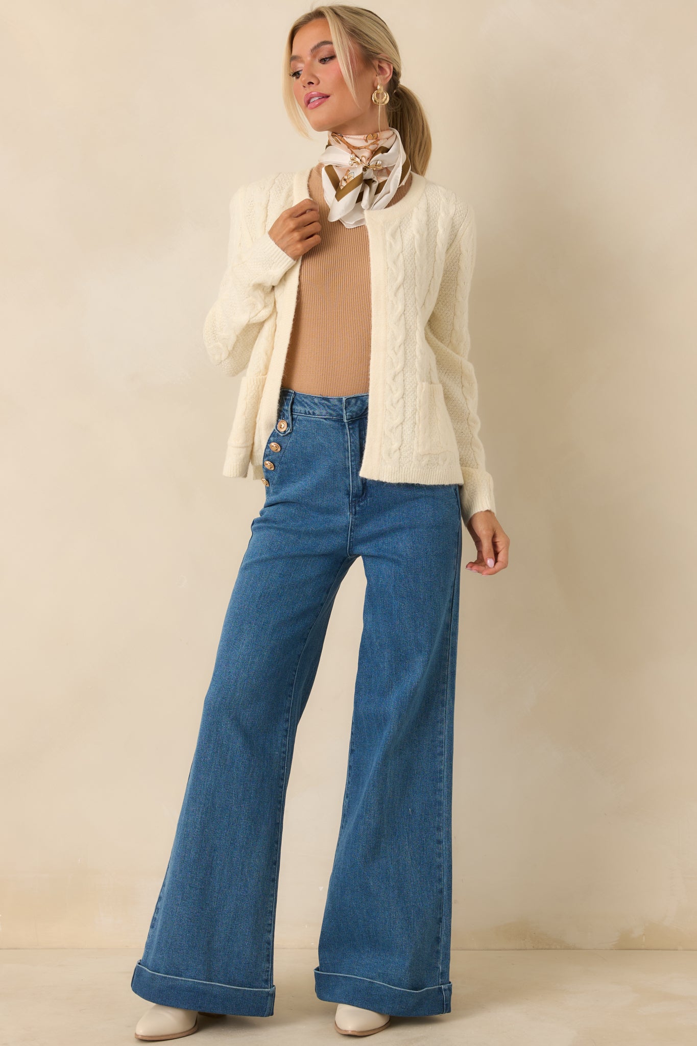 Relaxed-fit ivory cable knit cardigan with patch pockets, ribbed hem, and long sleeves for effortless layering.