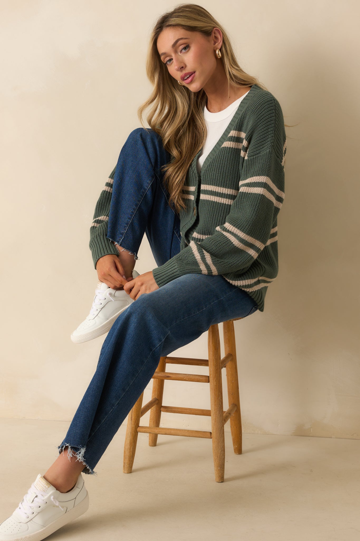 Relaxed green ribbed knit cardigan with horizontal beige stripes, long sleeves, V-neckline, and front button closure.