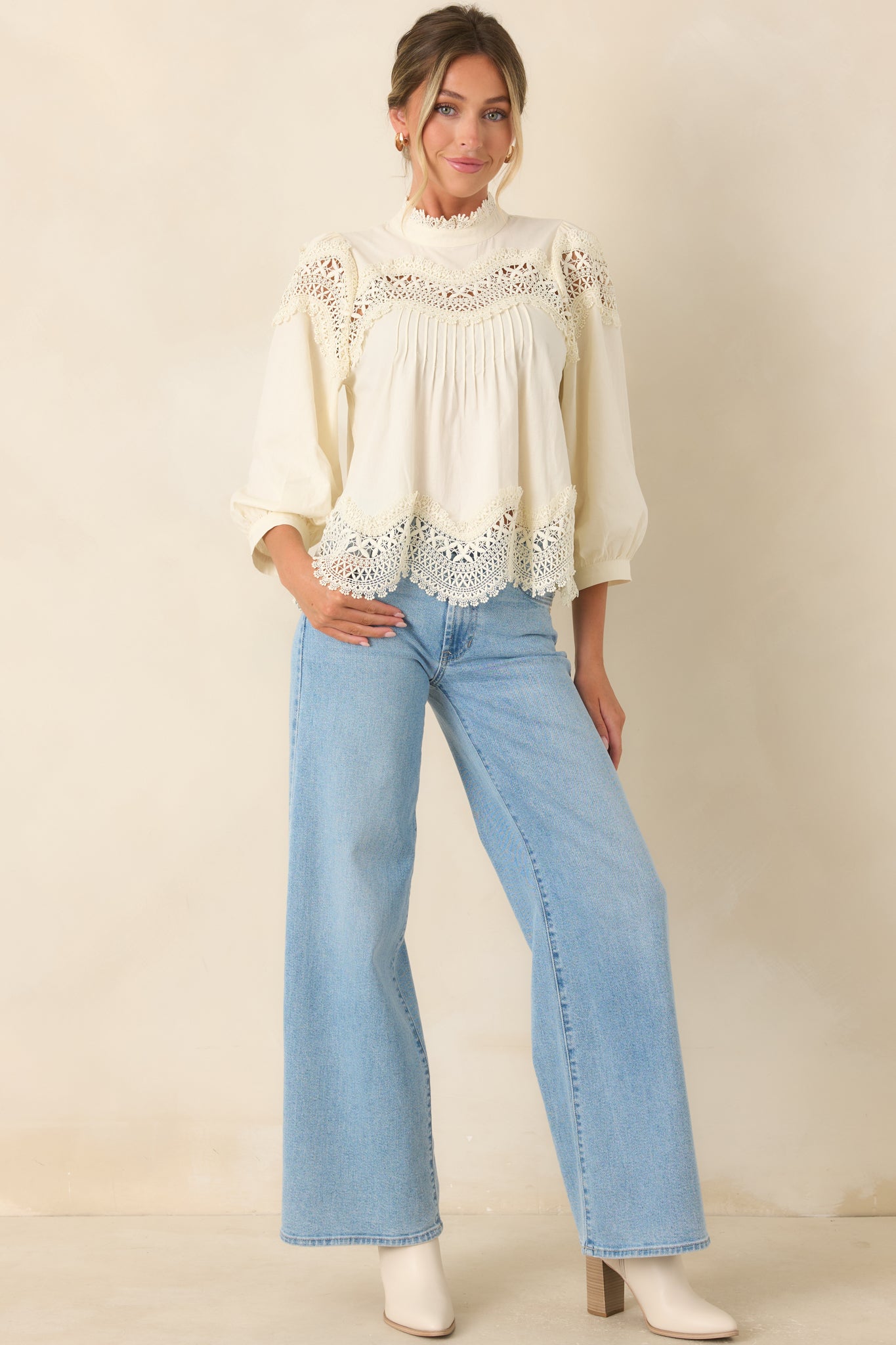 Relaxed ivory blouse with front pintuck detailing, lace accents, and a softly voluminous sleeve silhouette.