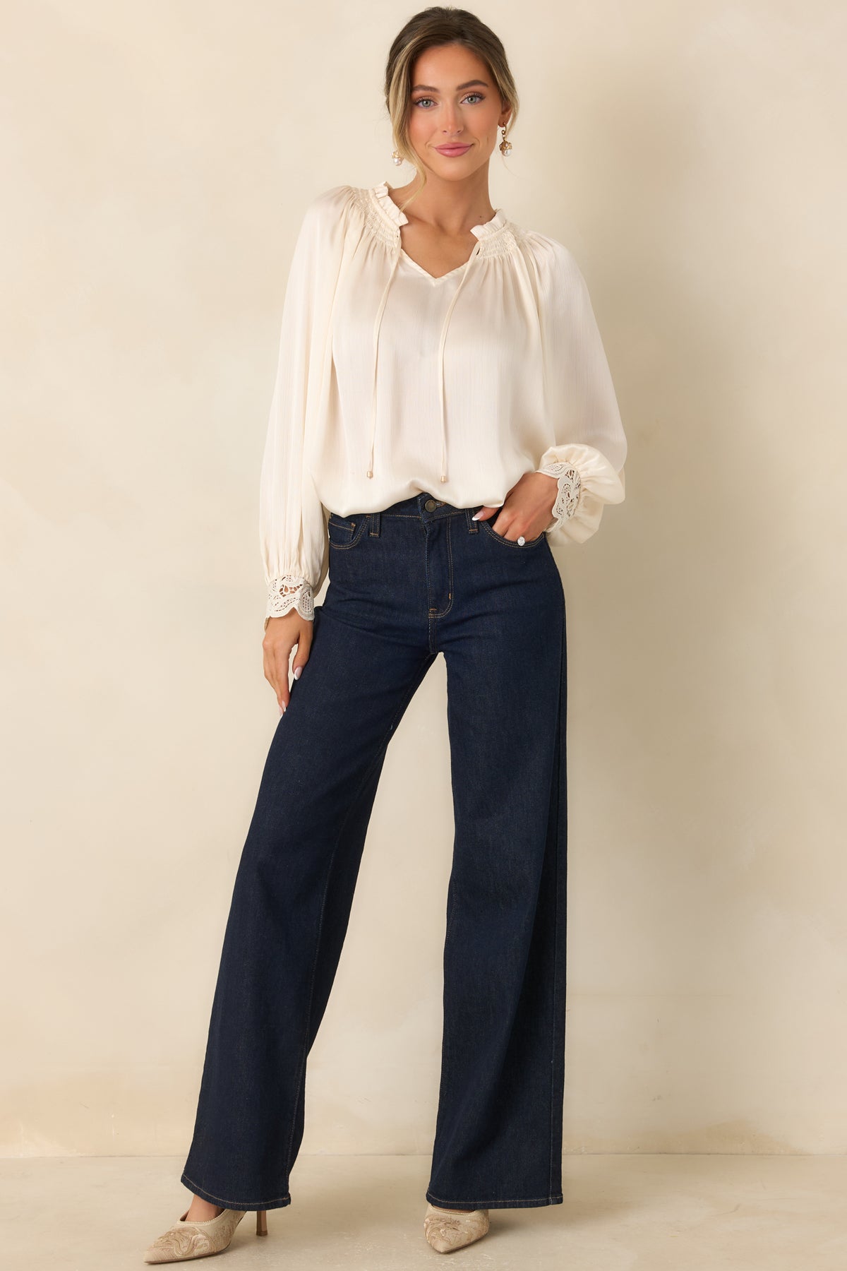 Long-sleeve blouse features a softly gathered V-neckline, flowing body, and voluminous sleeves finished with detailed lace cuffs.