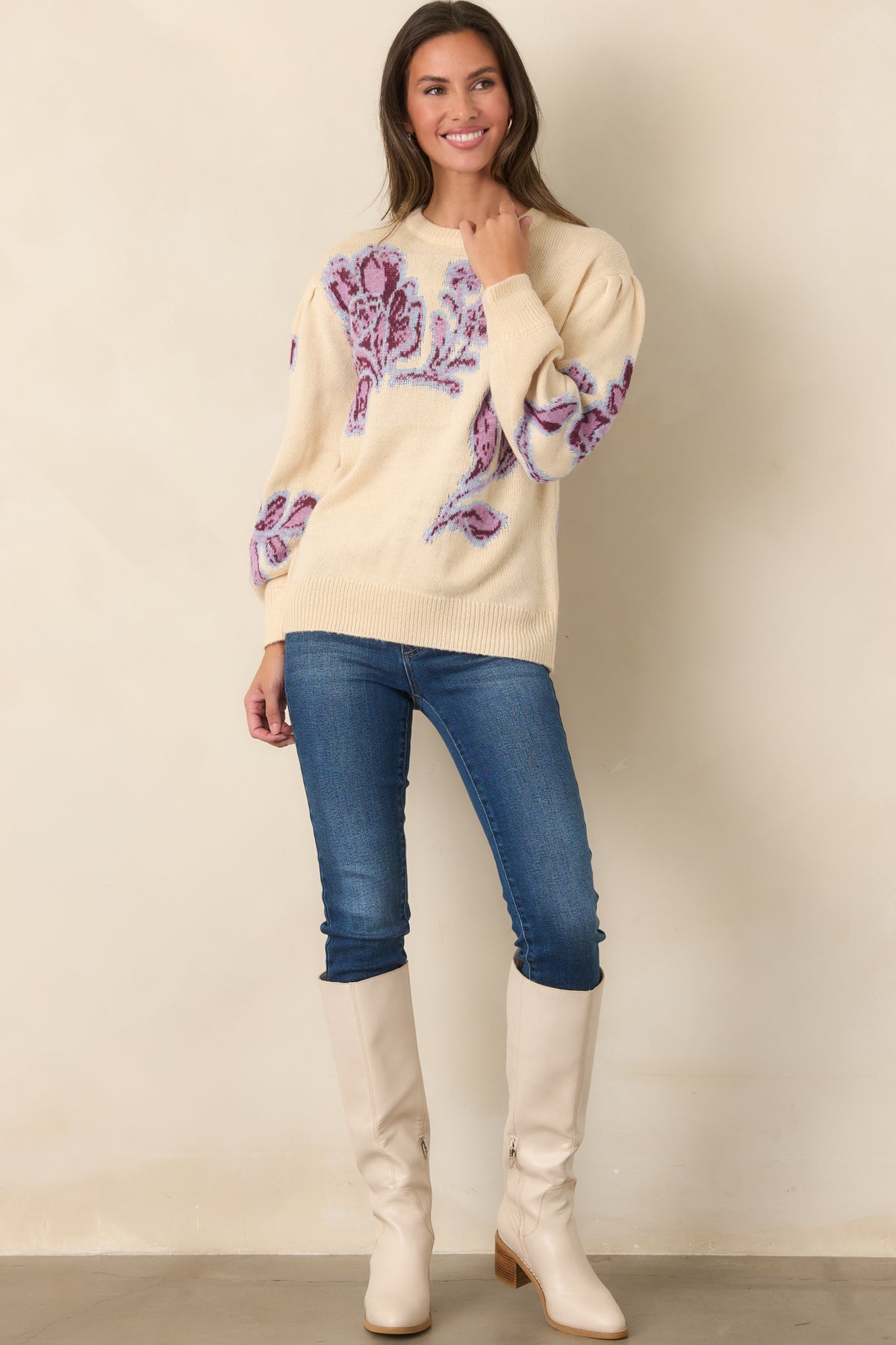 Relaxed vanilla knit top showcases oversized blooms across the bodice and long sleeves, finished with ribbed edges