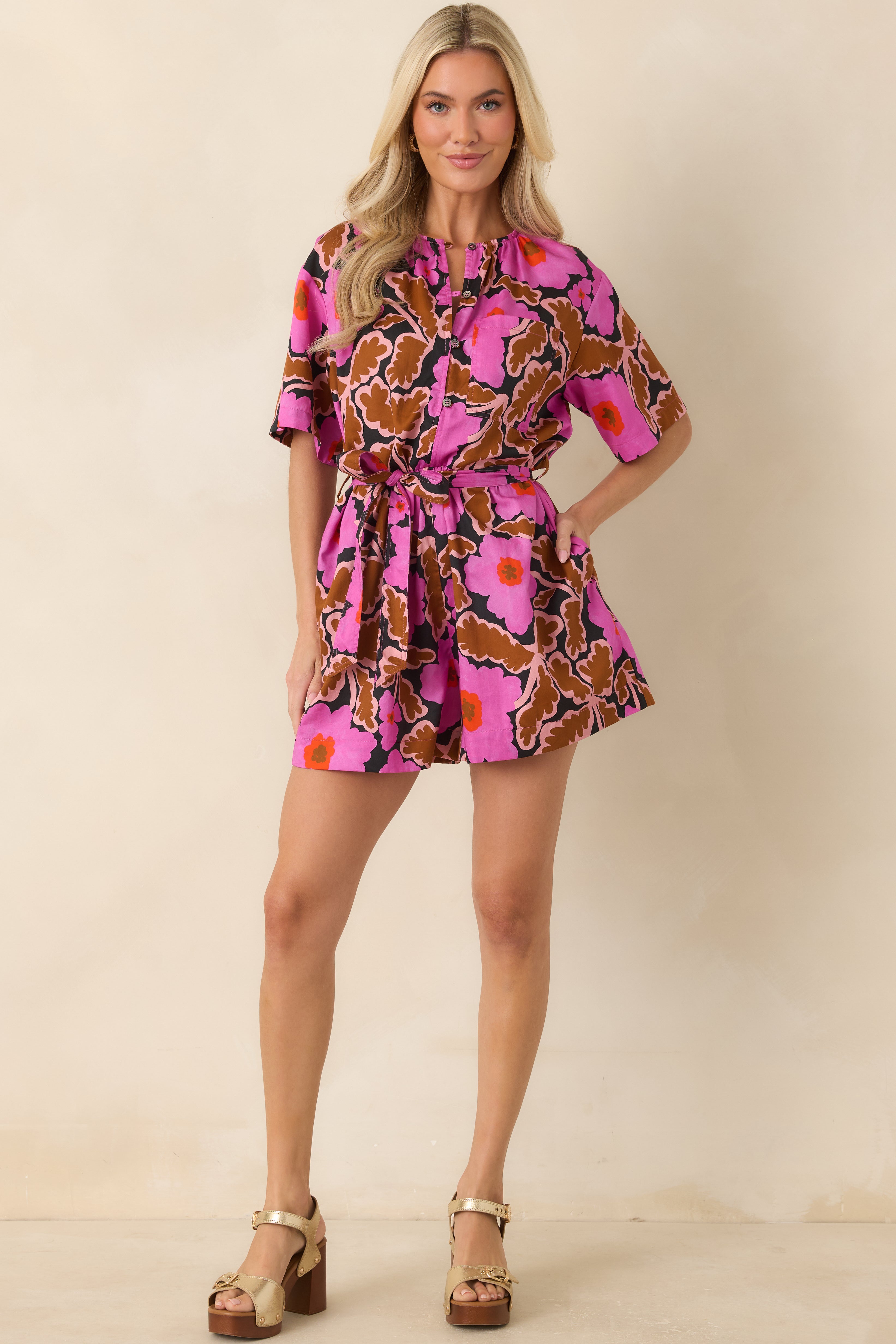 Retro-inspired floral romper featuring a relaxed shape, short sleeves, partial button neckline, self-tie waist, and lightweight construction.