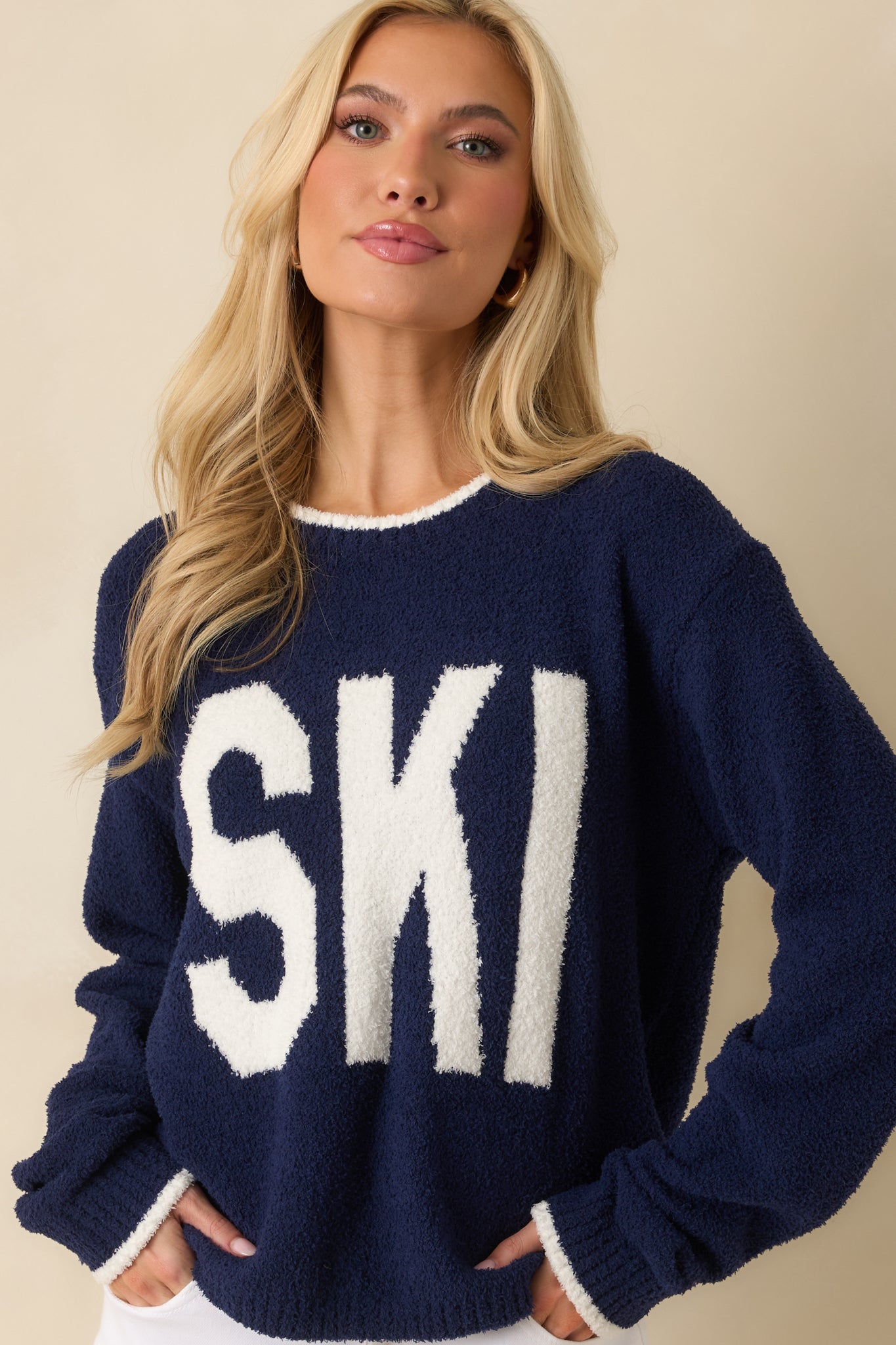 Ribbed hem and lower portion of the white graphic on the navy sweater.