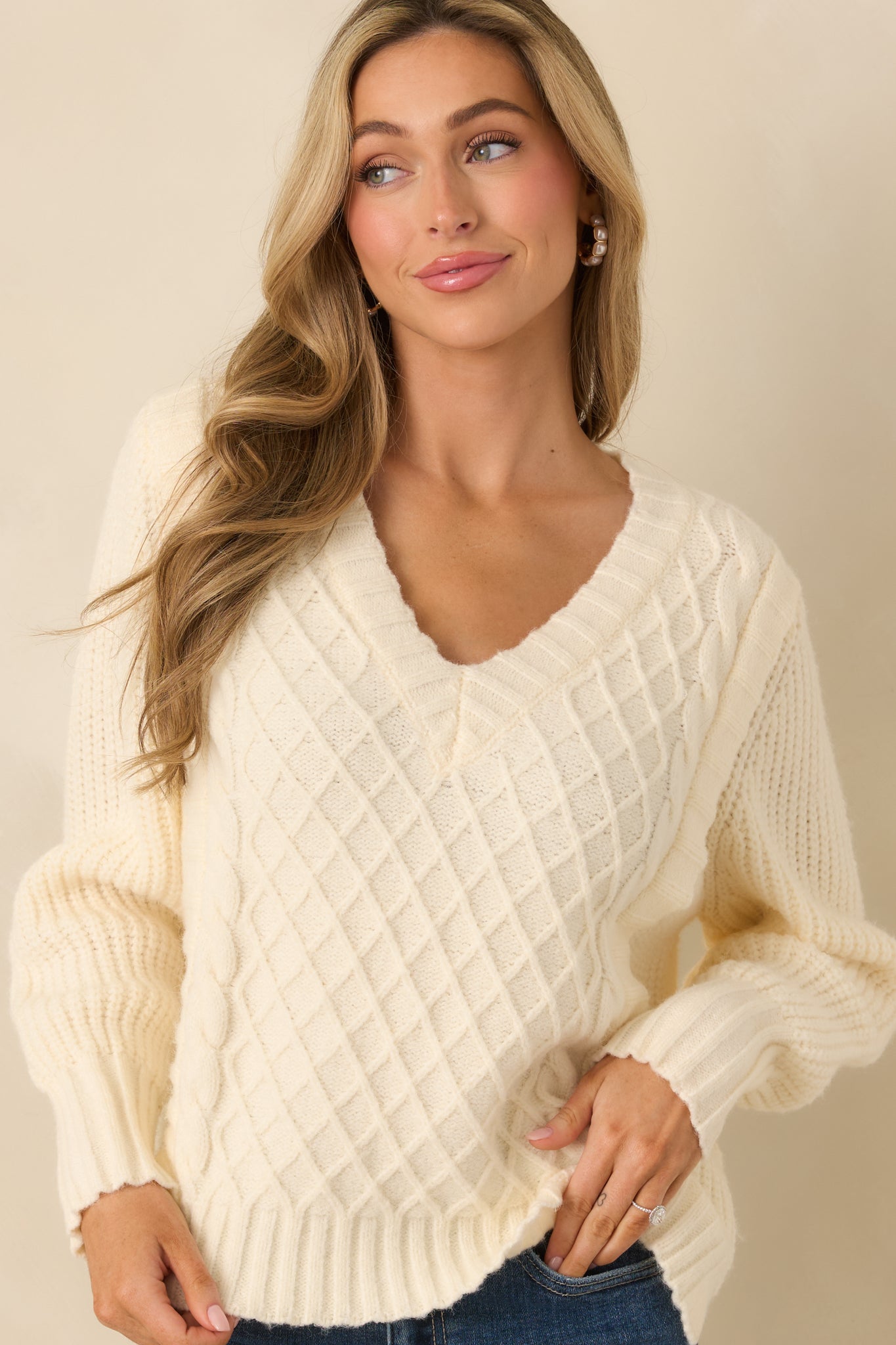 Ribbed hemline of ivory knit sweater with a soft, flexible stitch finish.