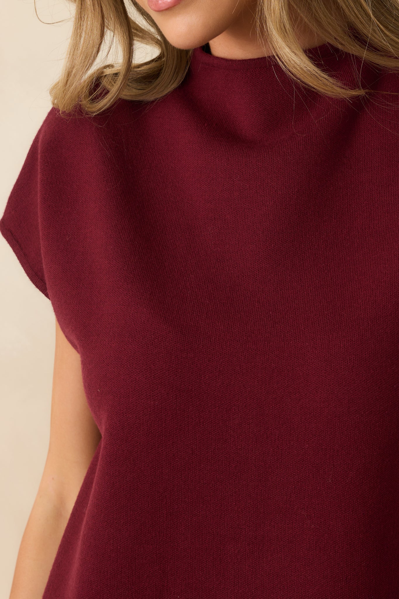 Detailed view of the ribbed knit fabric, mock neckline, and short cap sleeve design of the burgundy mini dress.