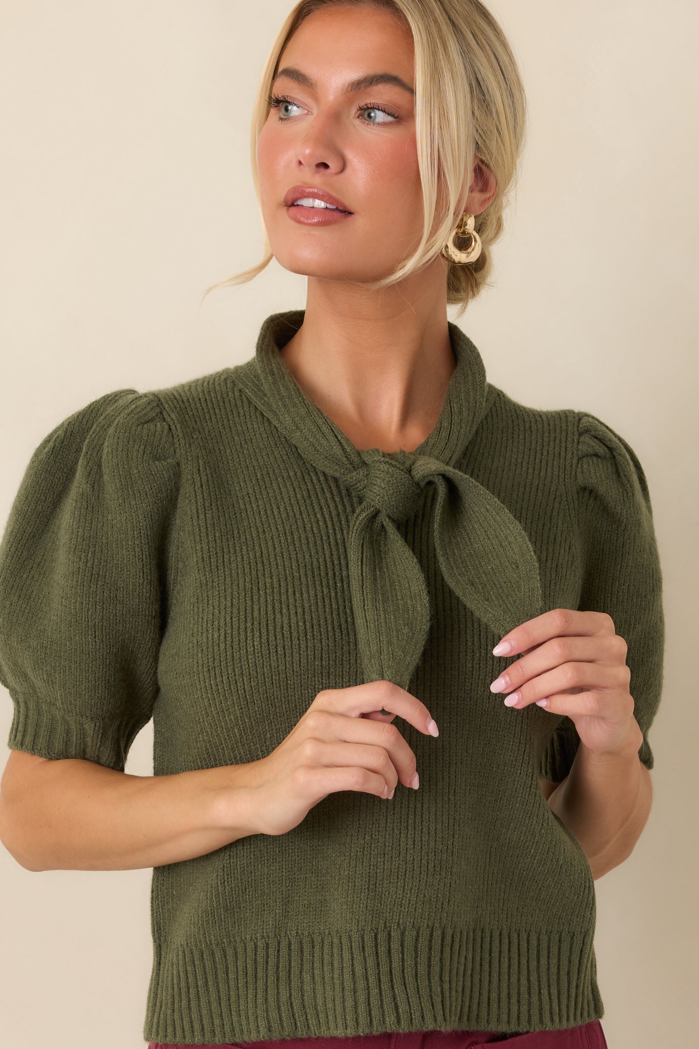 Detailed view of the ribbed knit top highlighting the oversized self-tie neckline and textured fabric.
