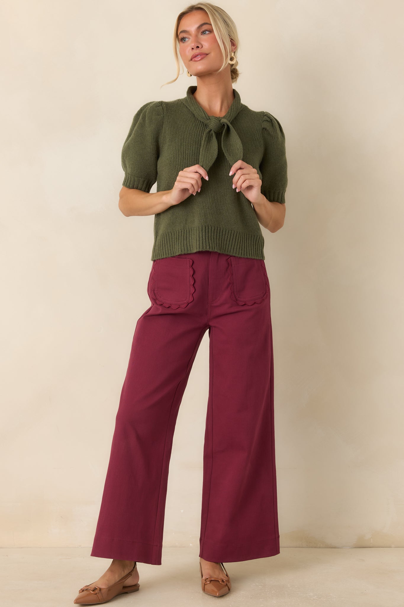 Ribbed knit top featuring an oversized self-tie neckline, puff sleeves, and a fitted silhouette with a ribbed hem.