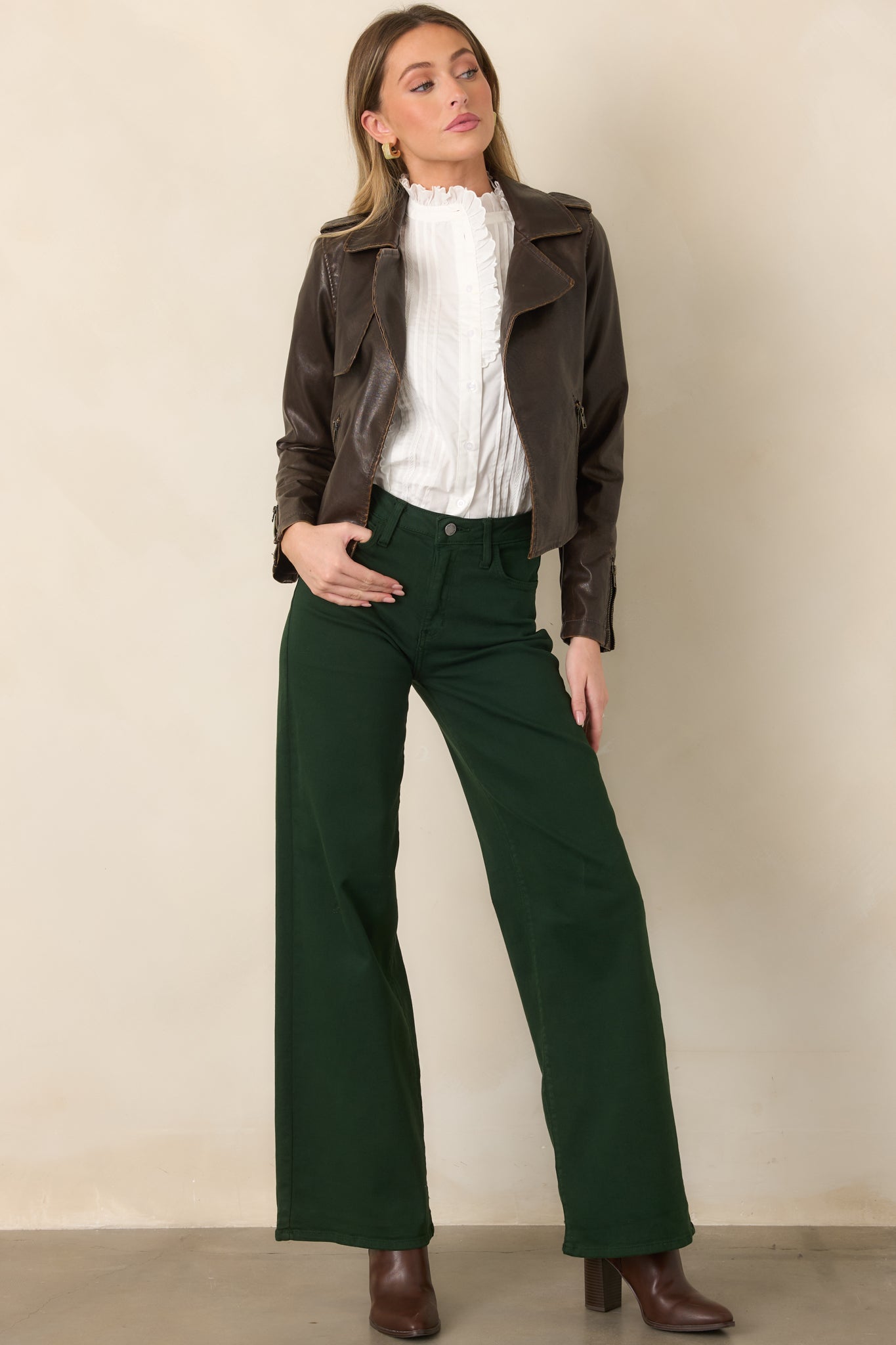 Rich brown jacket featuring a streamlined cropped silhouette, zippered side pockets, broad lapels, and polished faux leather construction.