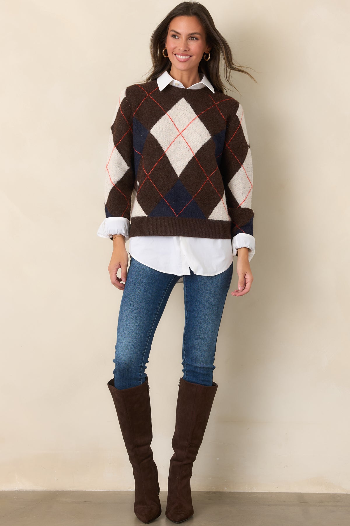 Rich brown sweater top featuring contrasting ivory and navy diamond motifs with fine rust-red accents, a classic crew neckline, and long sleeves.