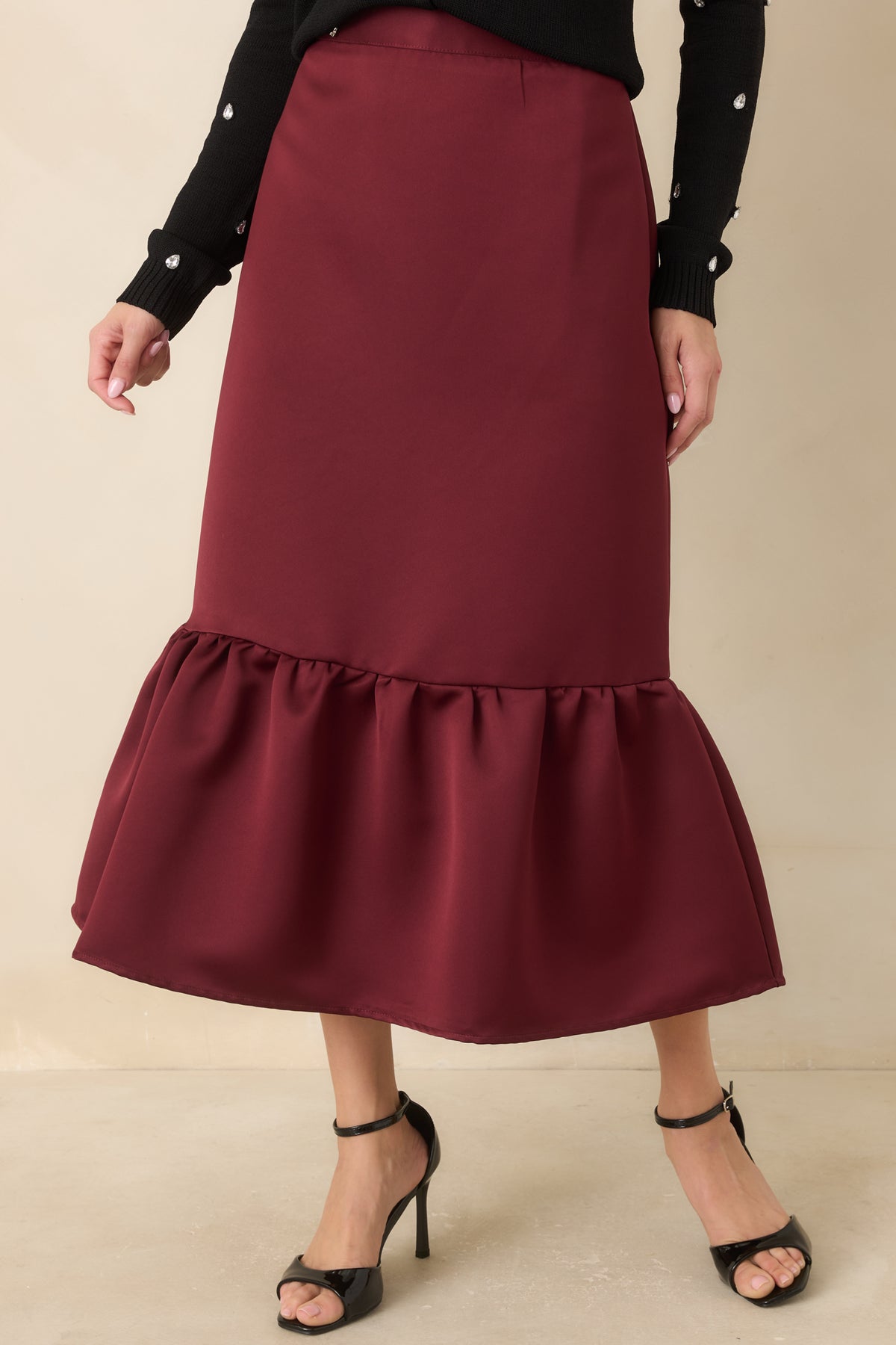Rich burgundy satin midi skirt showcasing its smooth finish and fitted shape.