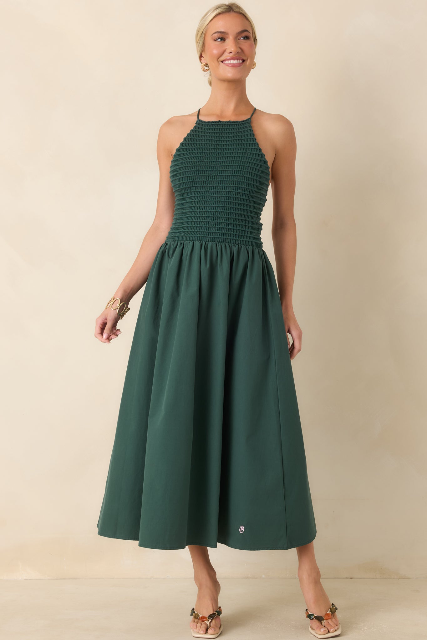 Rich green midi dress showcasing a sleeveless halter neckline, fitted knit bodice, and softly draped cotton skirt with graceful movement.