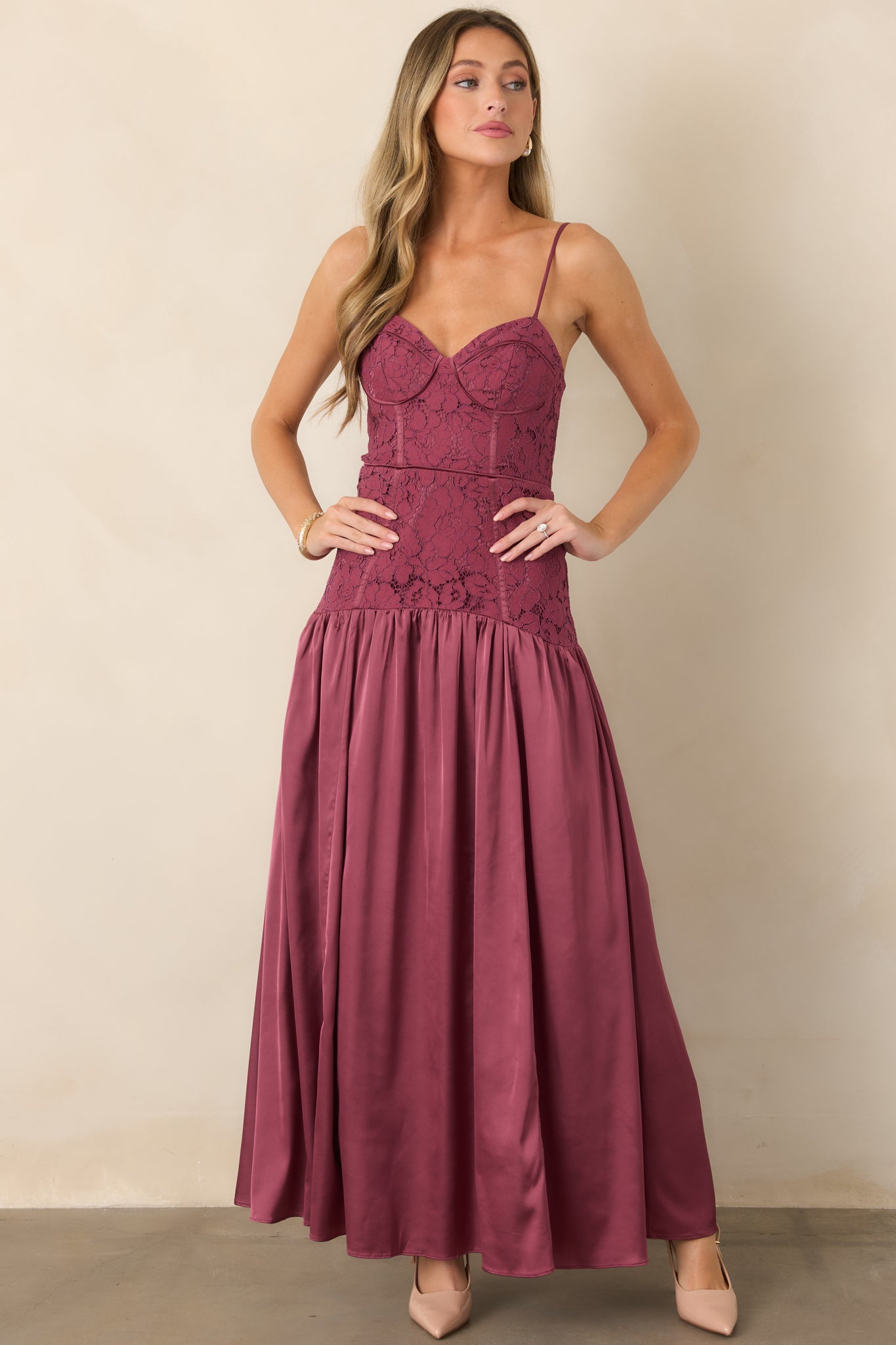 Romantic maxi dress displaying a textured lace-covered bodice above a dropped waist and flowing satin skirt with soft tulle-supported fullness.