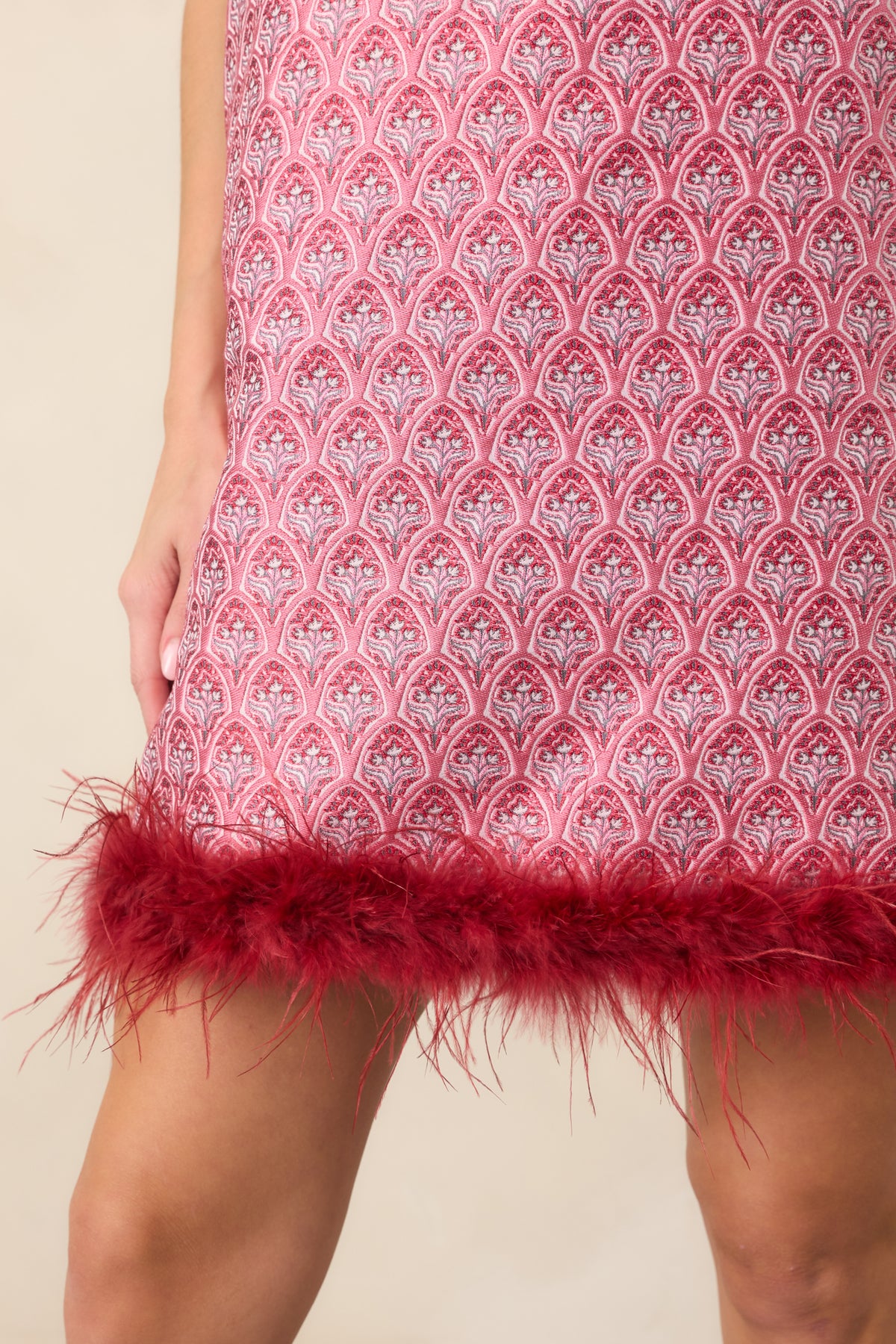 Close-up of the ornate rose pink and burgundy floral pattern with wispy burgundy feather trim along the hem.