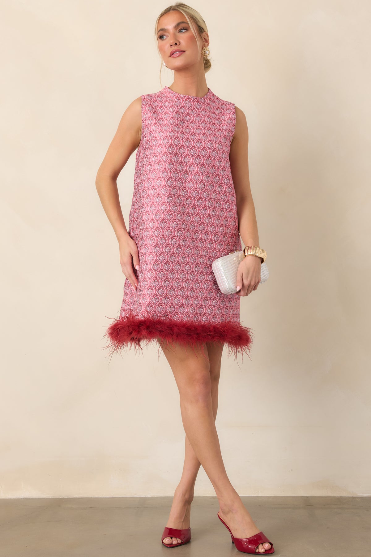 Rose pink and burgundy floral mini dress with a sleeveless silhouette, high round neckline, and wispy burgundy feather hem trim.