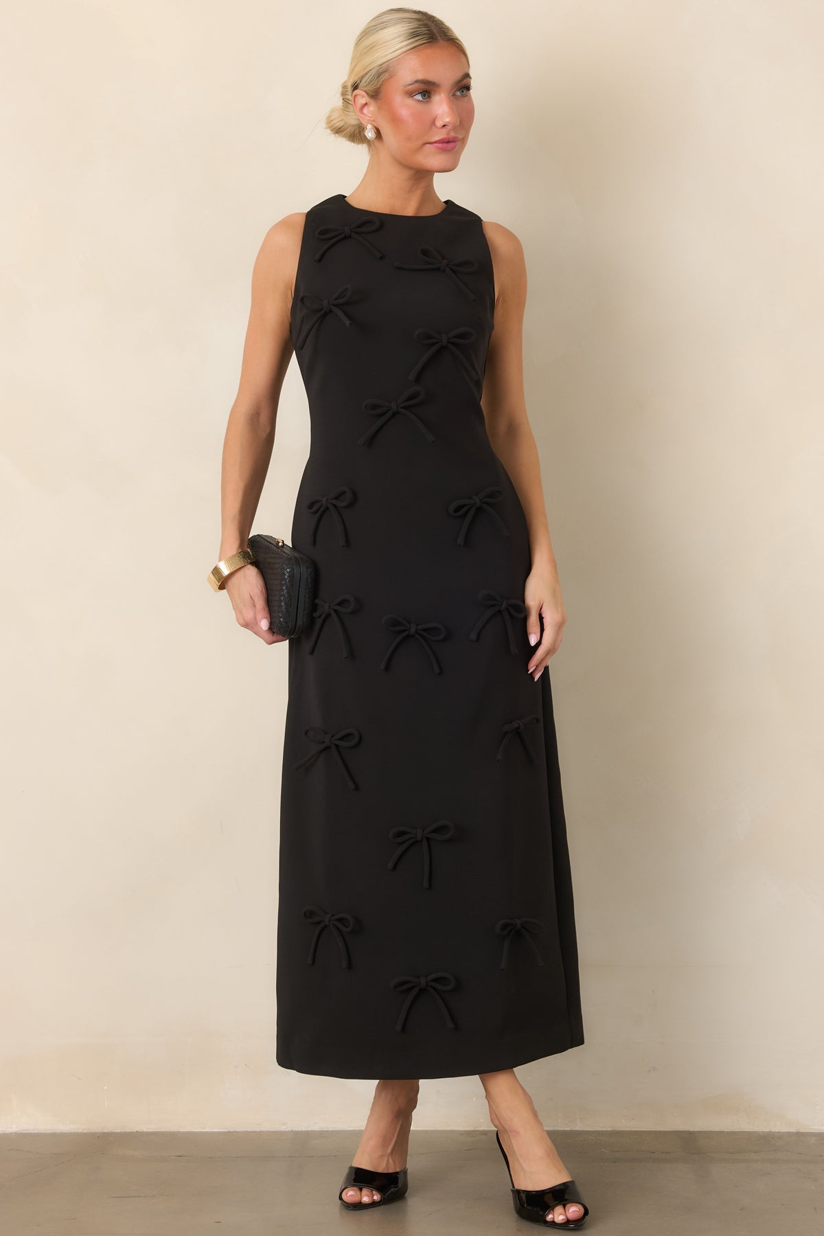 Polished sleeveless dress with a rounded neckline, shaped bodice, and long streamlined skirt accented by dimensional bows.
