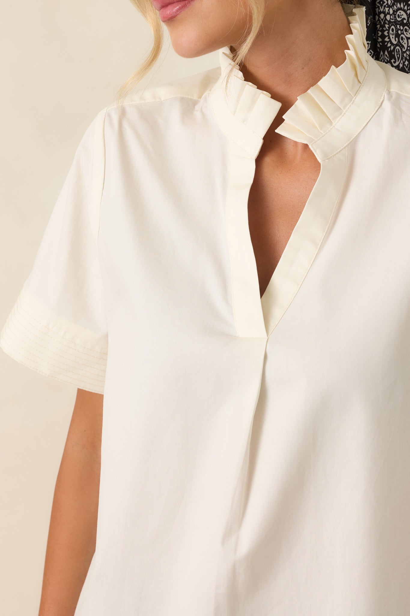 Detailed view of the pleated ruffle collar, split neckline, stitched cuffs, and breathable cotton fabric.