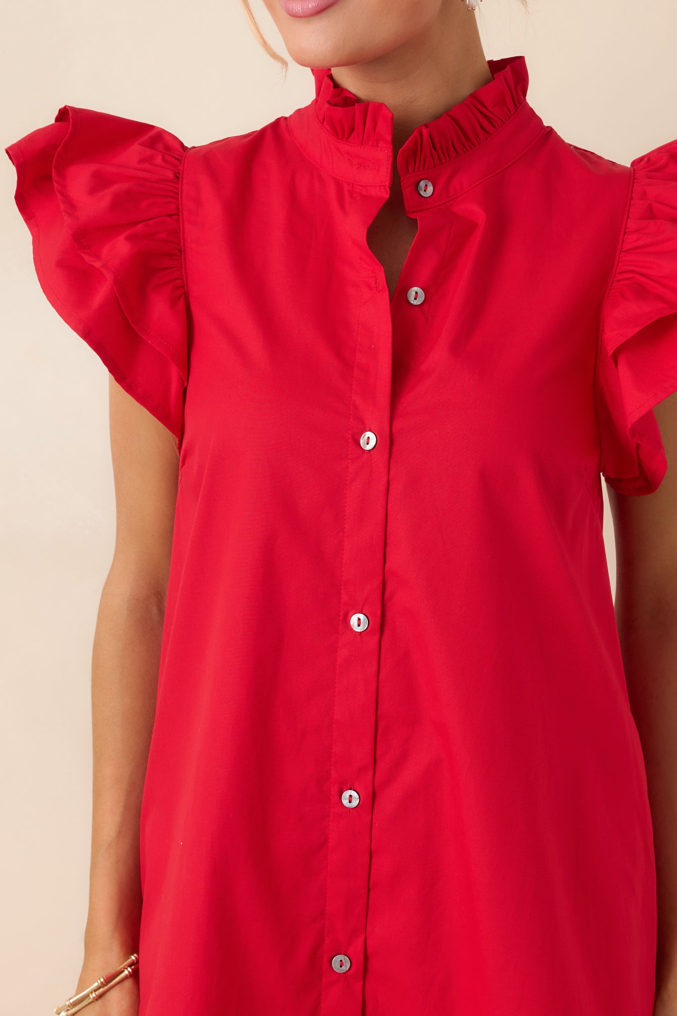 Ruffle-trimmed collar, flutter sleeve, and button-front detail on red cotton fabric.