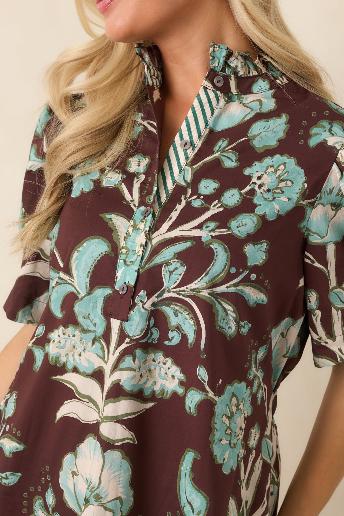 Close-up highlights the ruffled stand collar, button-front placket, and aqua, ivory, and olive floral print.