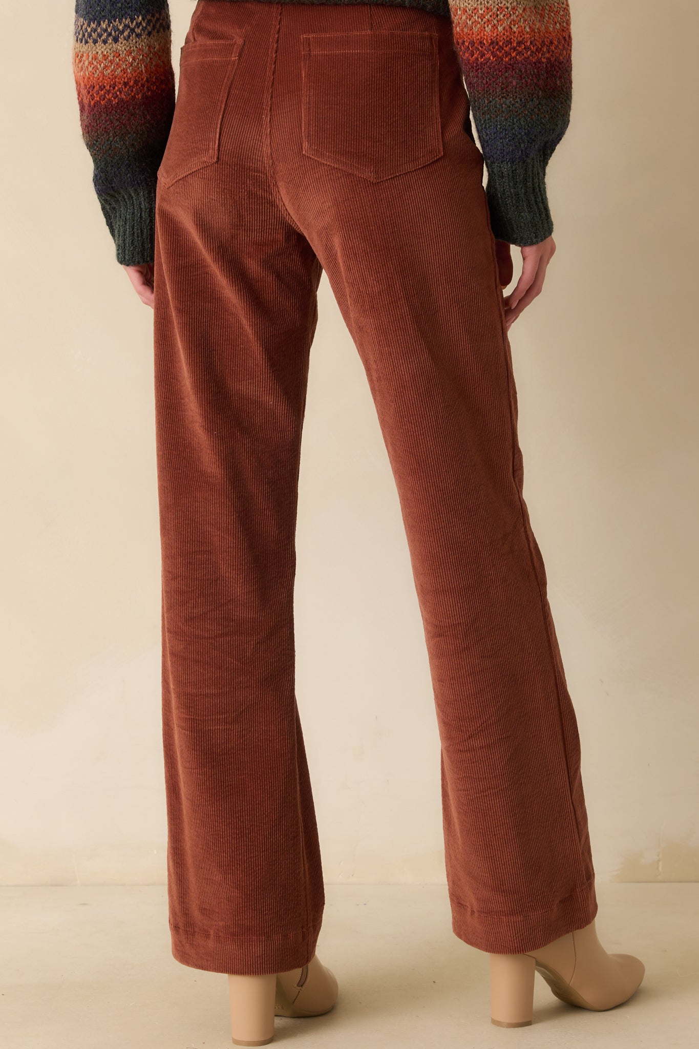 Rear view of the rust corduroy pants showing back patch pockets and straight-leg cut.