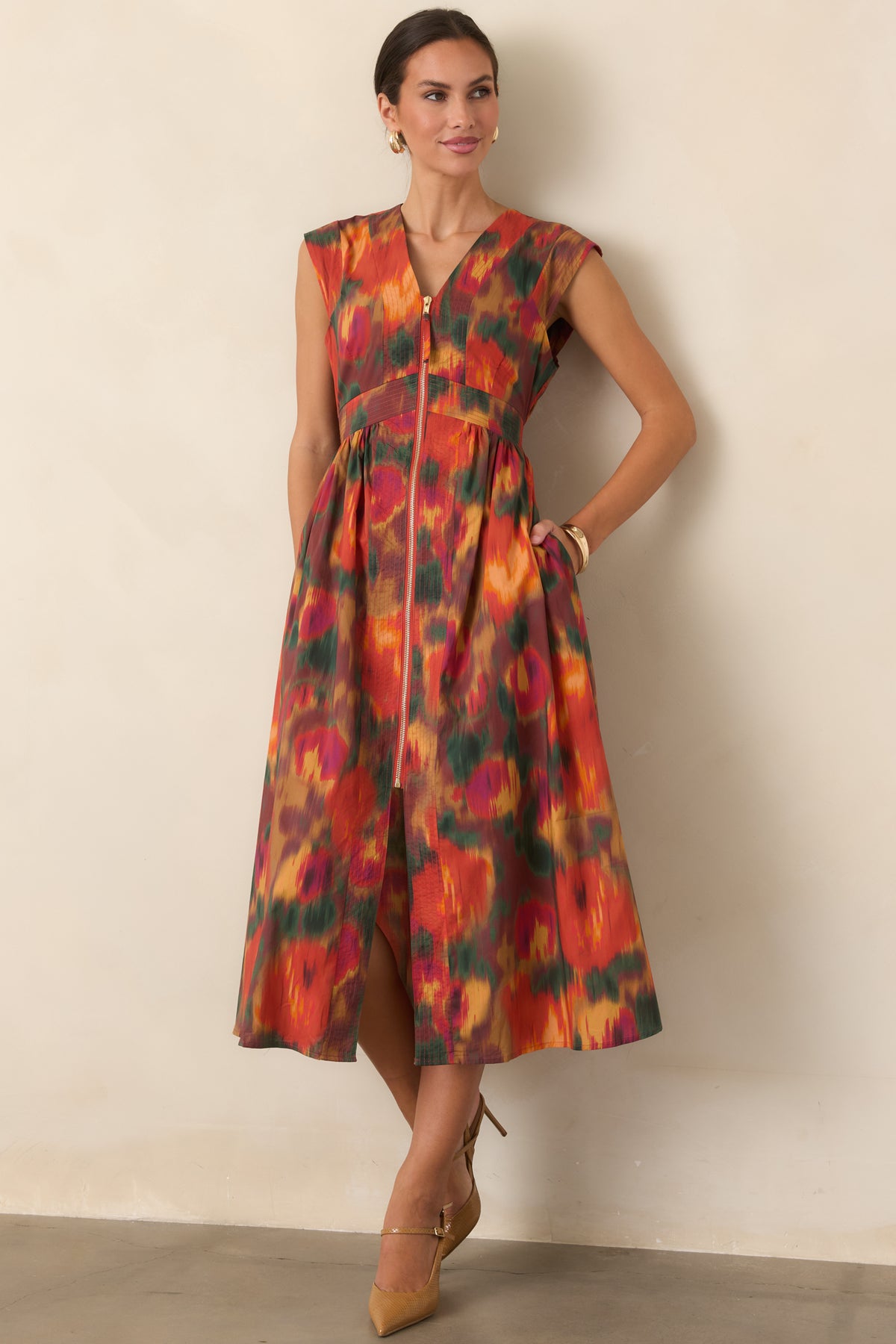 Rich rust cotton midi dress featuring a painterly floral print, V-neckline, structured cap sleeves, defined waist, and gathered full skirt.