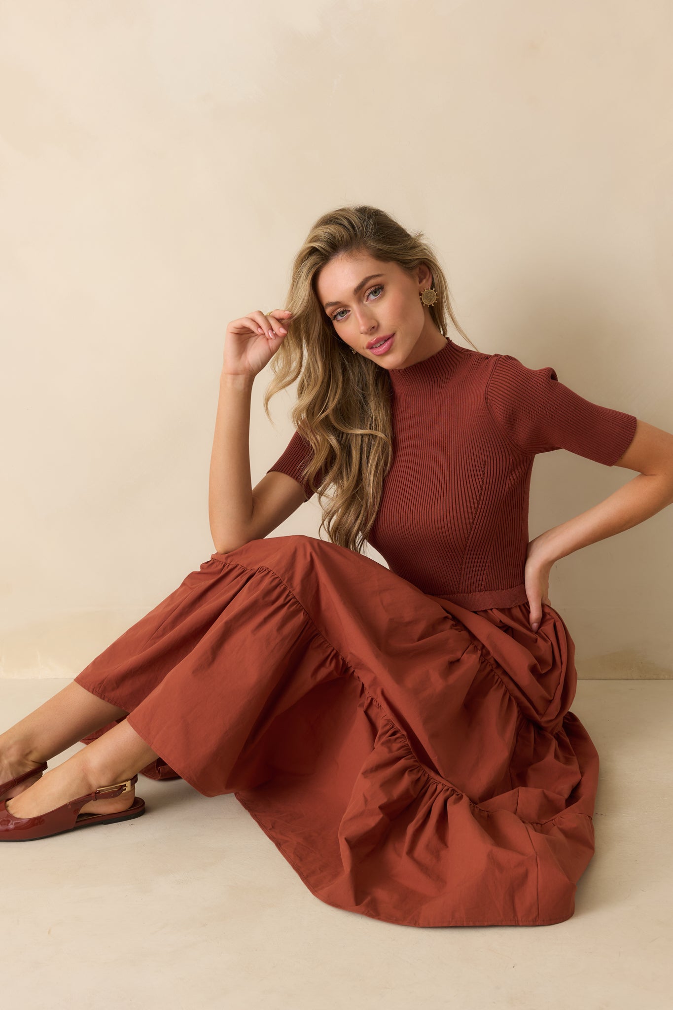 Rust red maxi dress showcasing a crew neckline, ribbed knit top, and flowing tiered skirt.